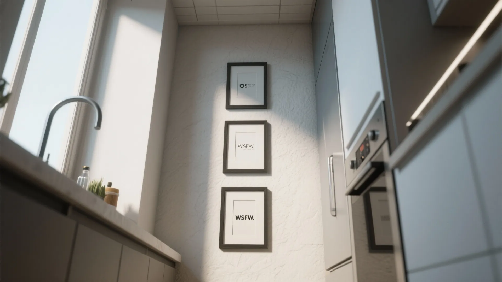 Three black framed pictures stacked vertically on a narrow white wall in a modern kitchen