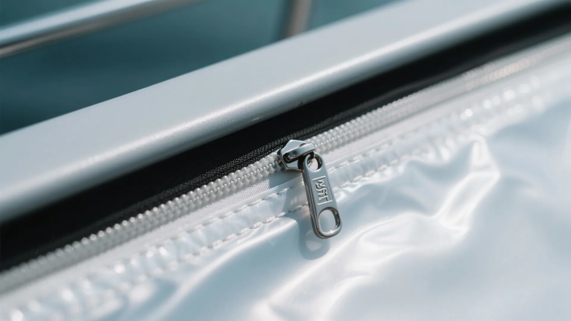 Macro of clear vinyl panel edge with stainless snaps, zipper, and neat stitching on a powder-coated frame.