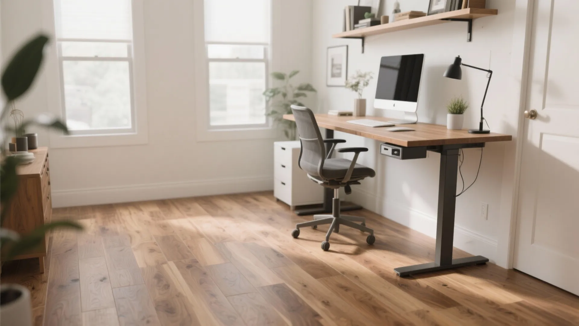 Modern home office featuring a wood standing desk with computer chair and light wood flooring