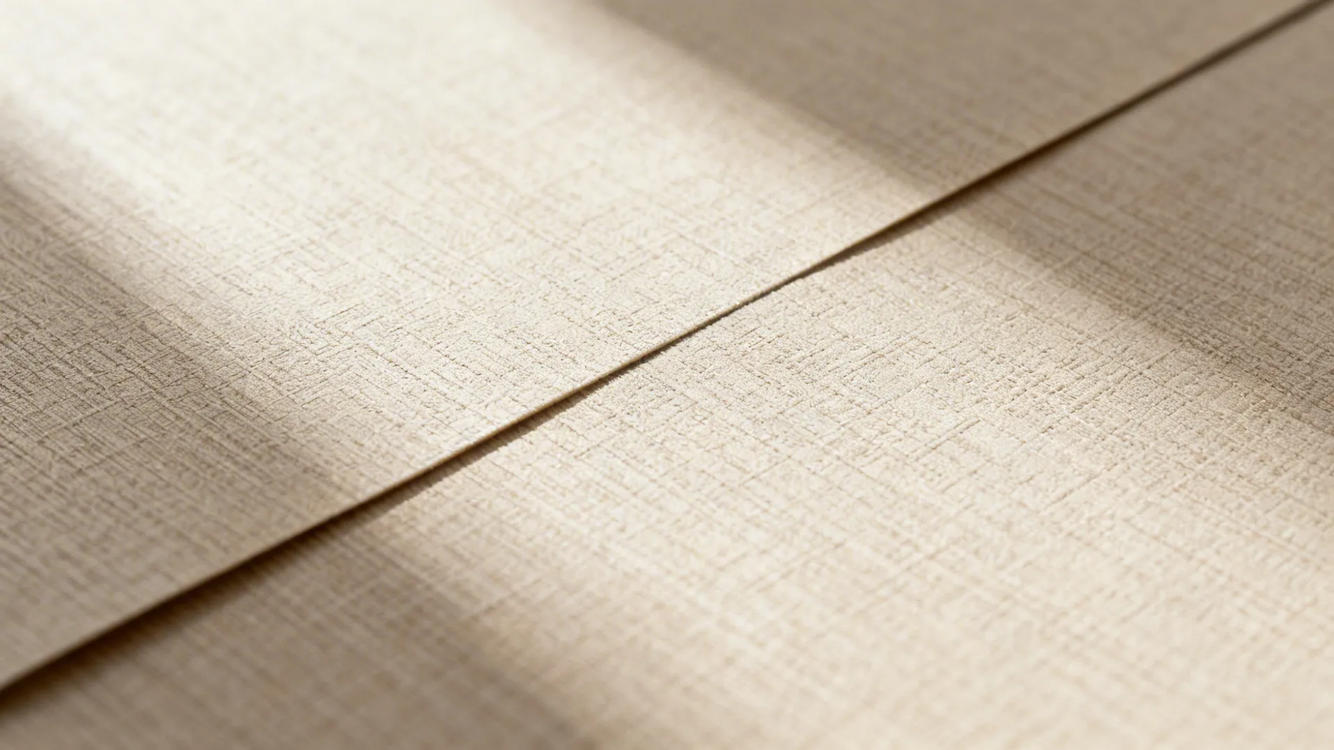 Close up of beige textured vinyl floor material with soft shadows and a visible seam