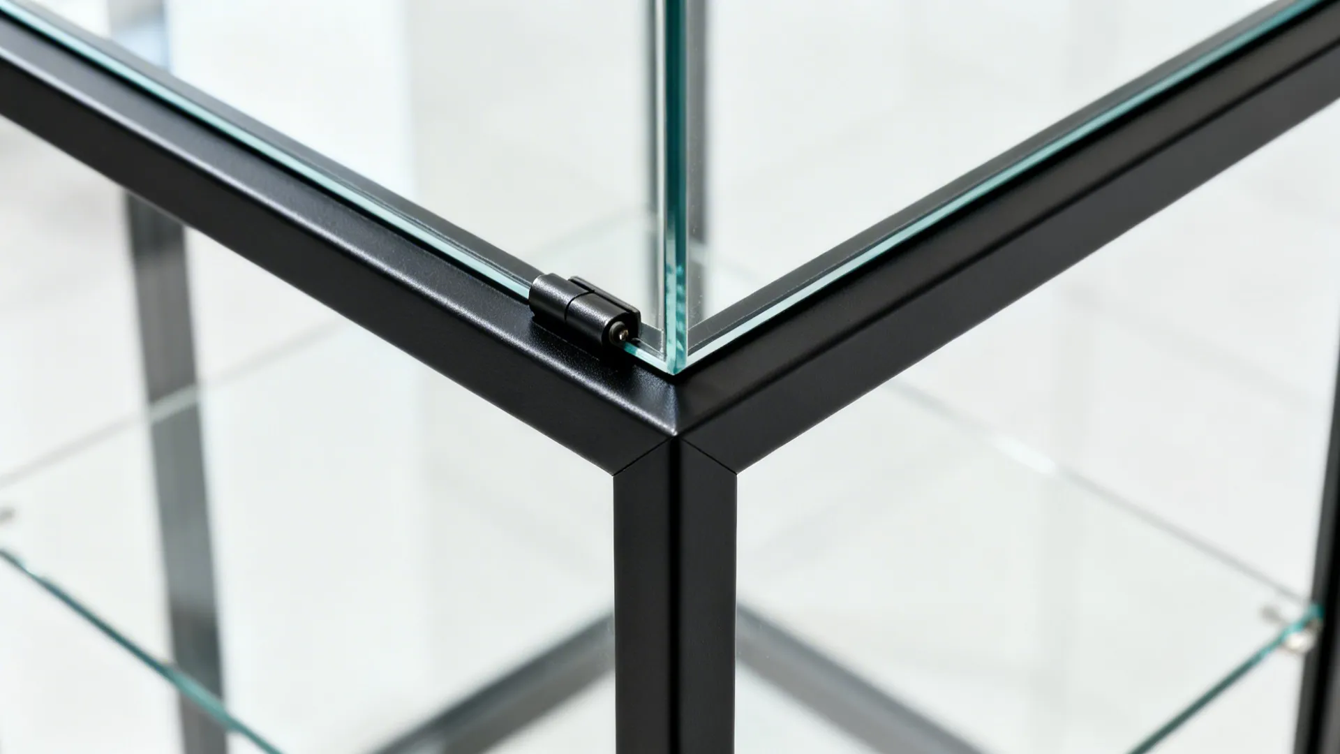 Macro corner detail of a thin black metal frame meeting clear tempered glass.