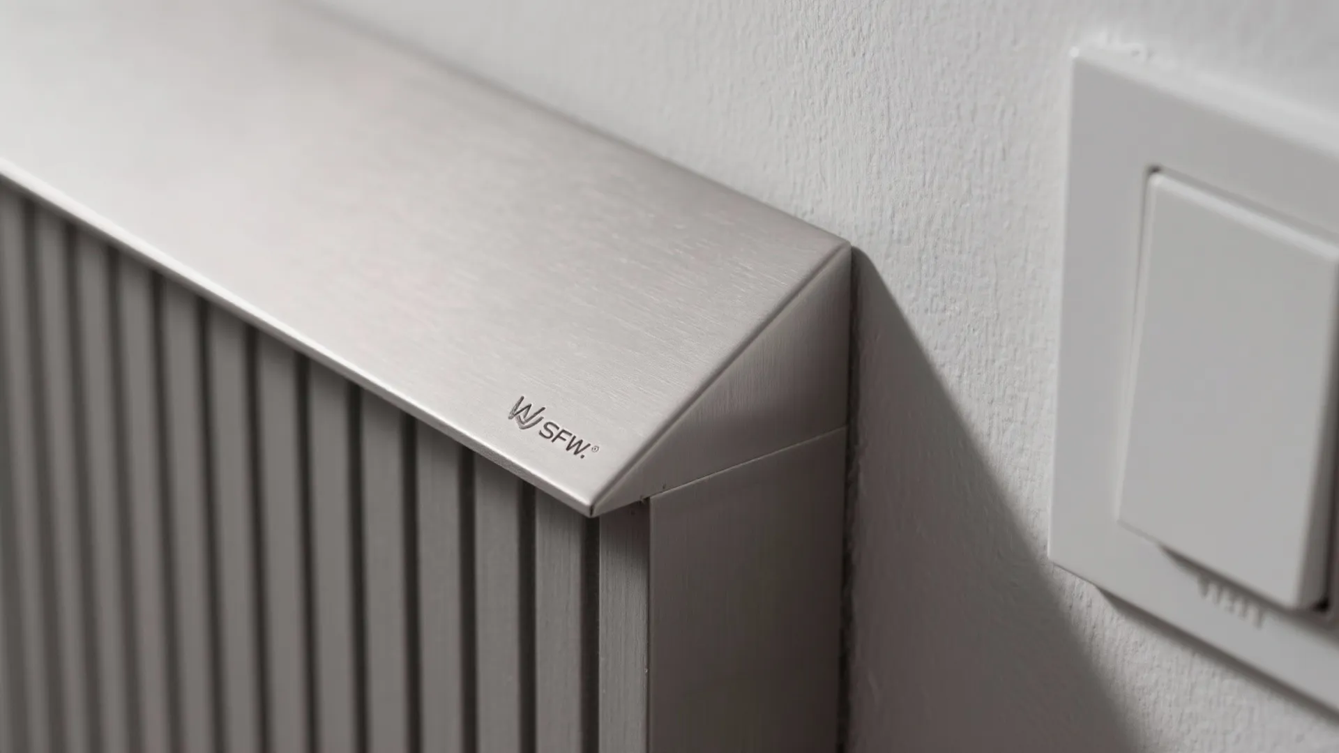 Close up view of a grey metal wall panel next to a white light switch