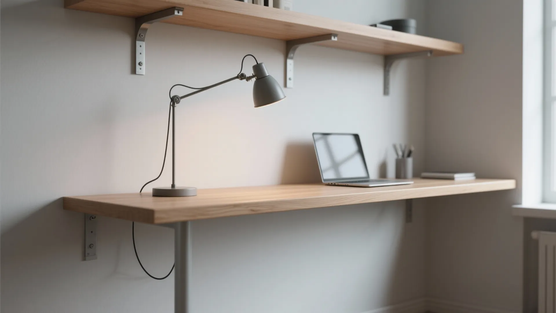 Minimalist wooden wall desk with a grey table lamp laptop and open shelving in home office