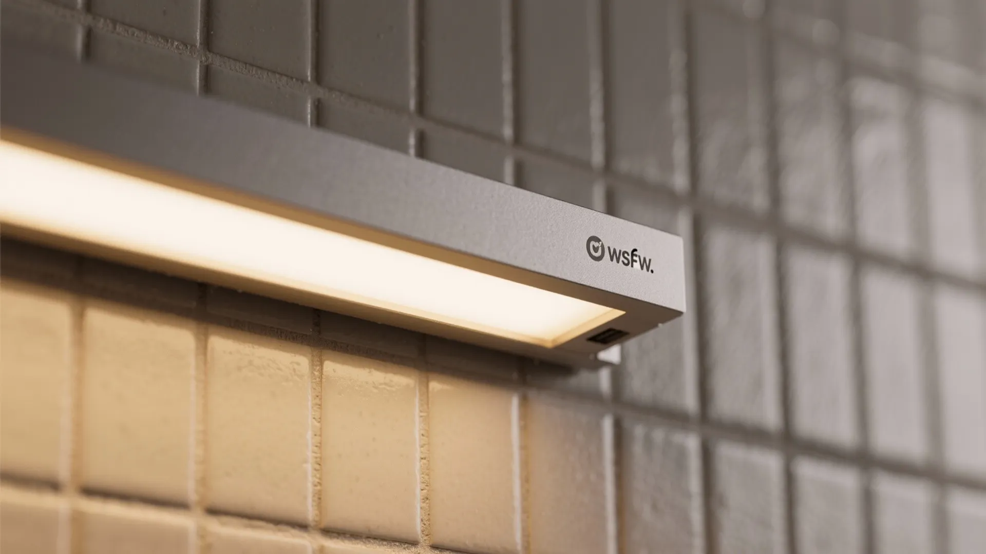 Close up shot of linear light fixture mounted on a grey tiled wall with warm glow