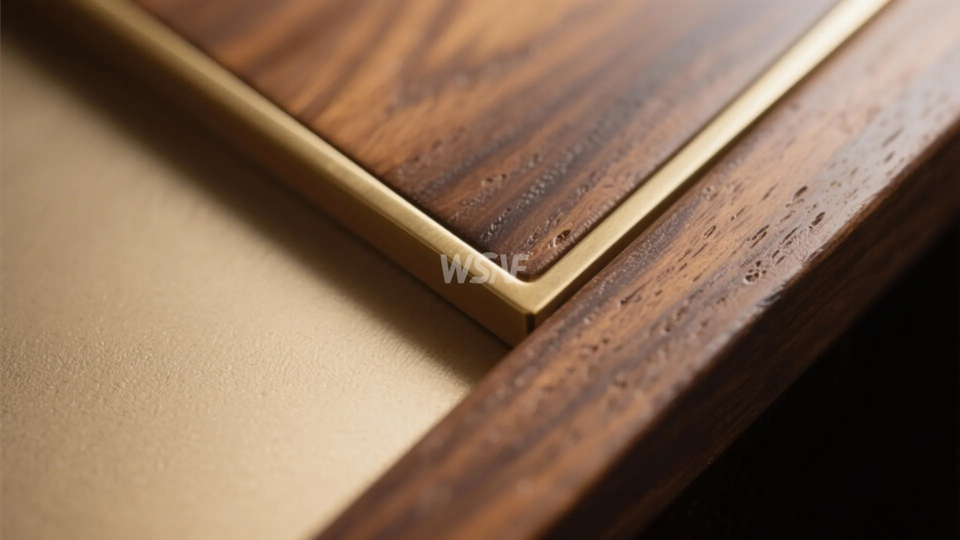 Close-up of walnut wood grain with a slim brass inlay under soft uplighting.