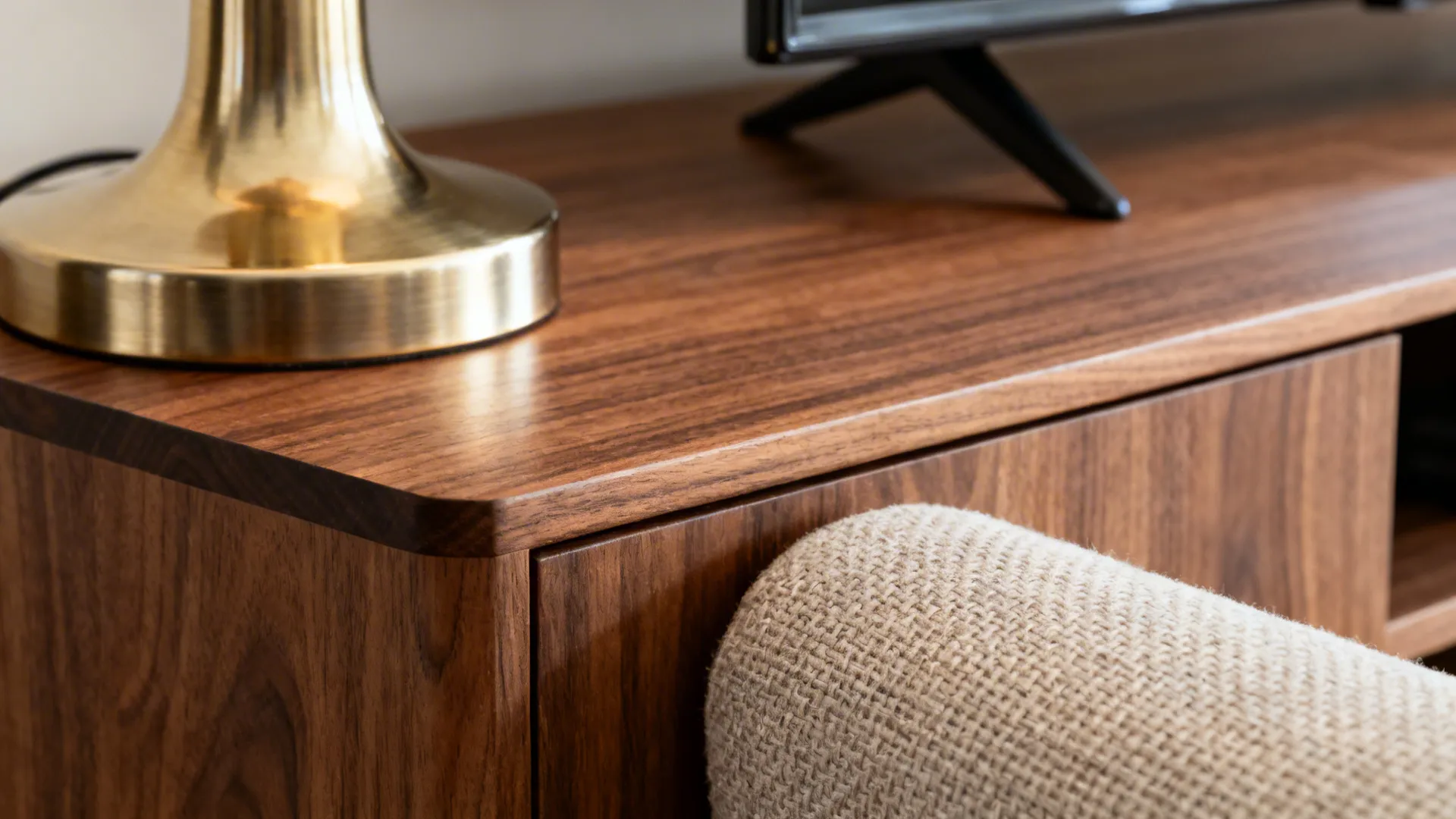 Close-up of walnut veneer edge and brushed brass lamp in soft daylight