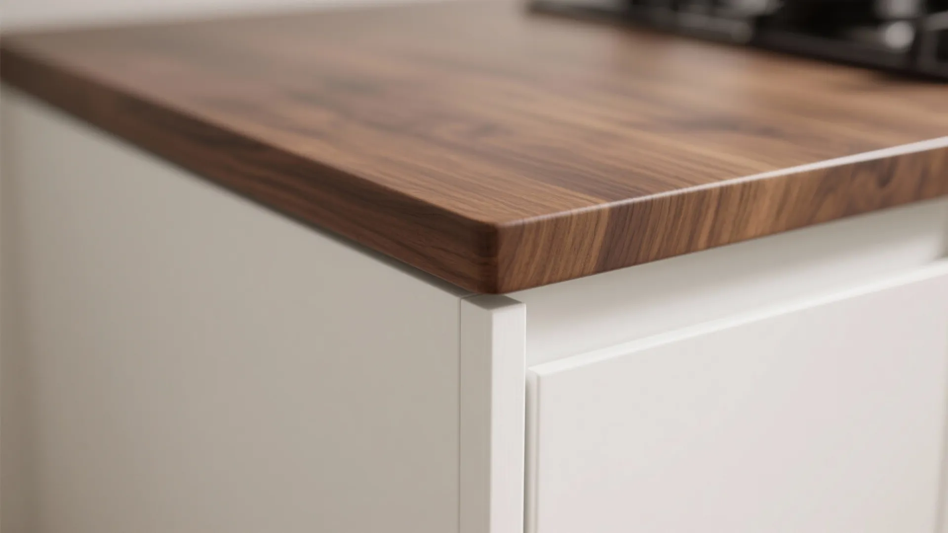 Detailed view of a dark wood countertop edge on top of white kitchen cabinet doors