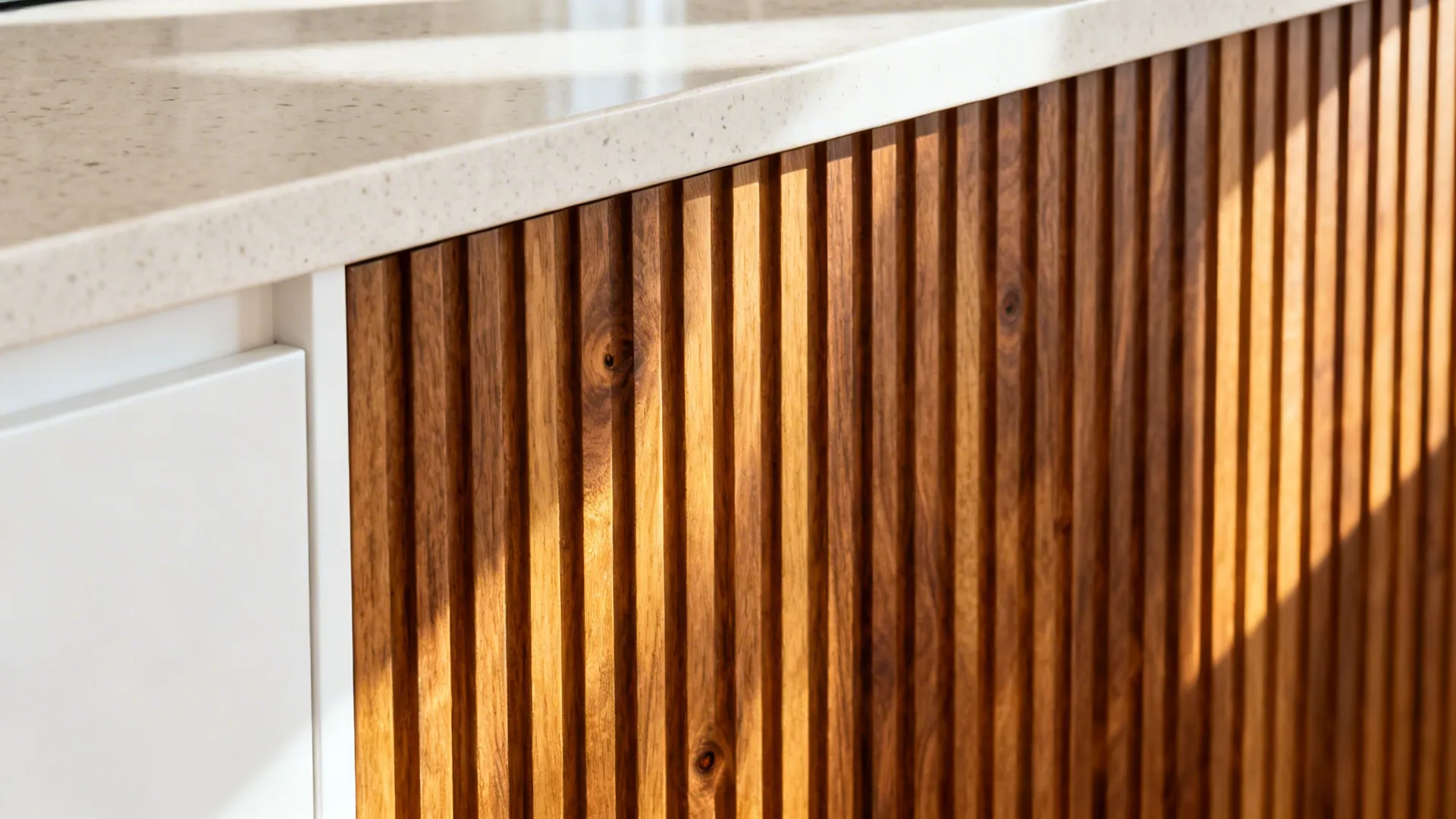 Close-up of ribbed walnut island panel with warm grain detail beside a light quartz counter.
