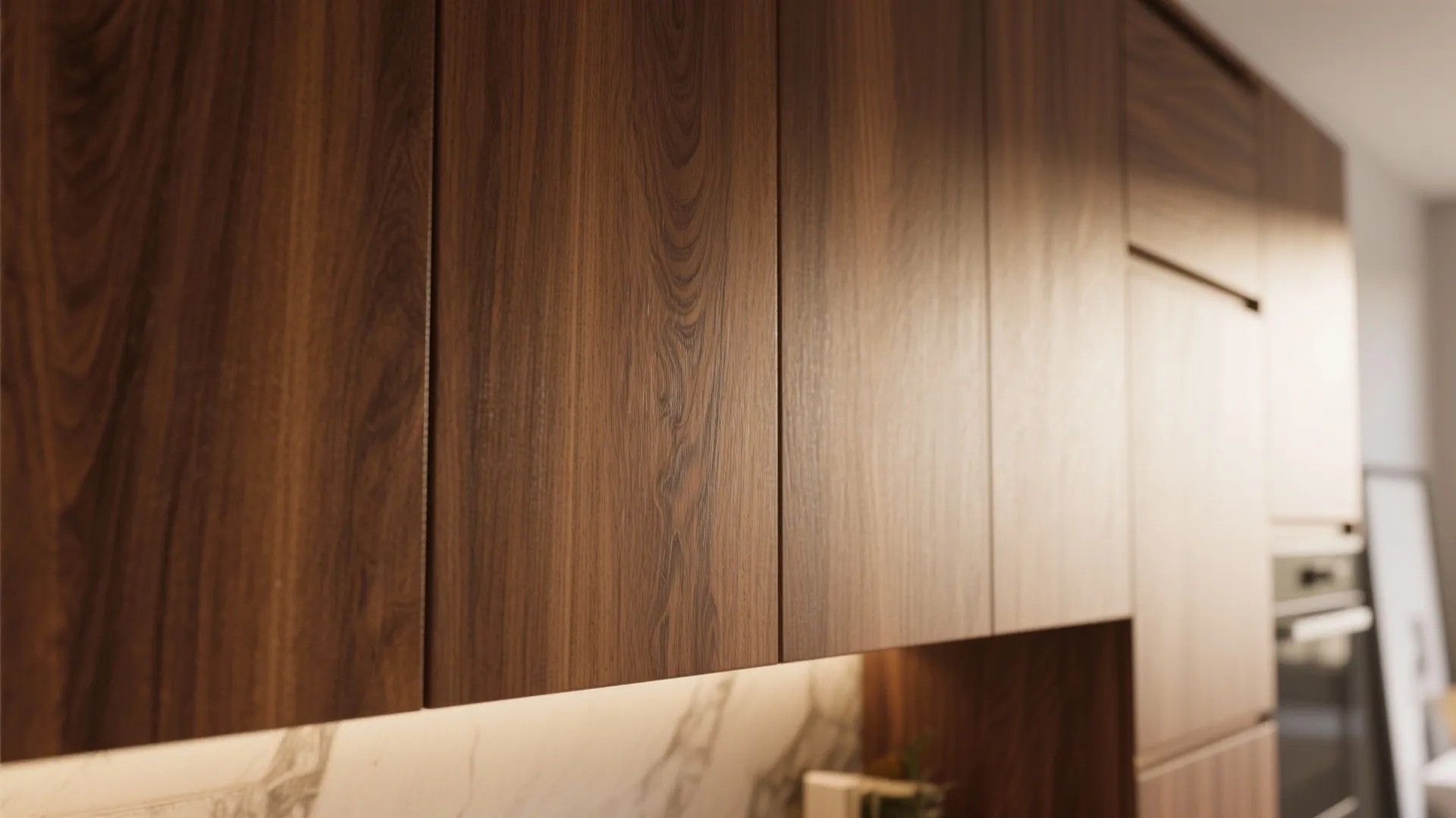 Close up of dark walnut wood kitchen cabinet doors with marble backsplash and under cabinet lighting