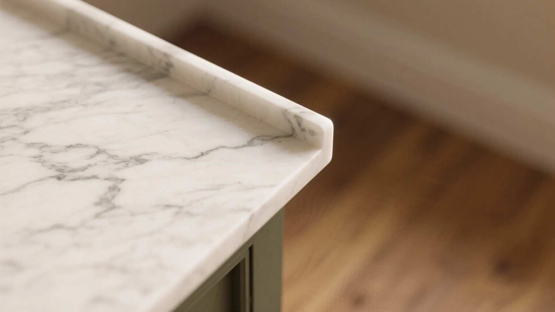 Close up view of a white marble kitchen countertop edge showing grey veins and wood floor