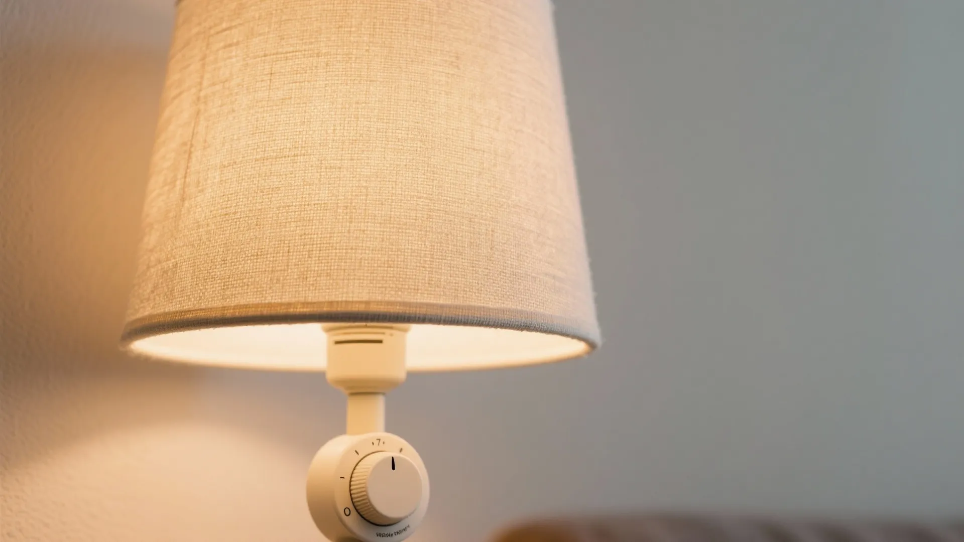 Macro of a linen-shade table lamp with warm 2700K glow and dimmer control.