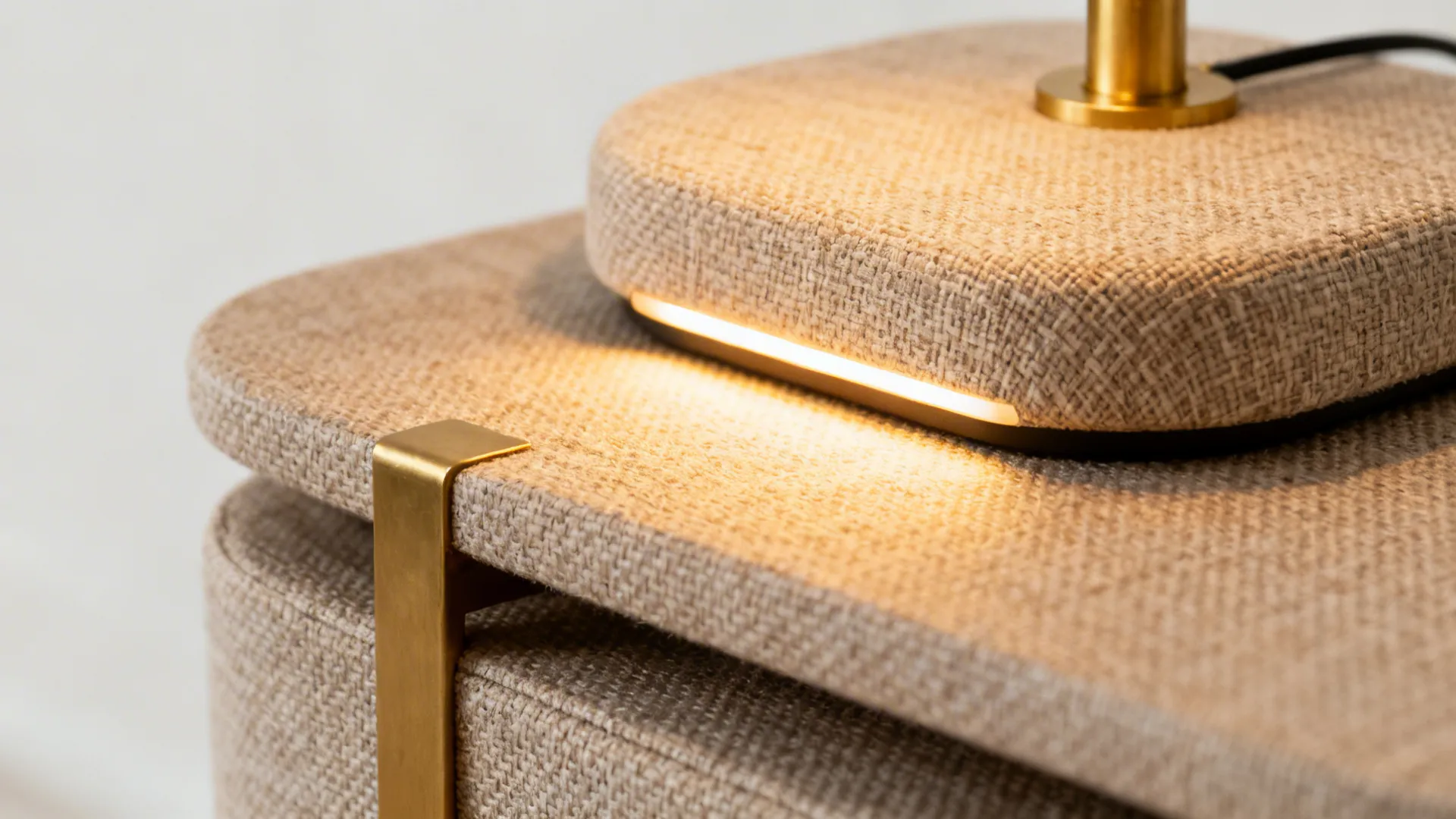 Macro of warm LED task light on linen upholstery with nesting table and brass accent