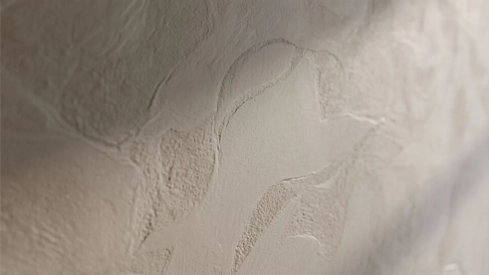 Close up view of warm beige wall plaster with wavy textured patterns and soft lighting