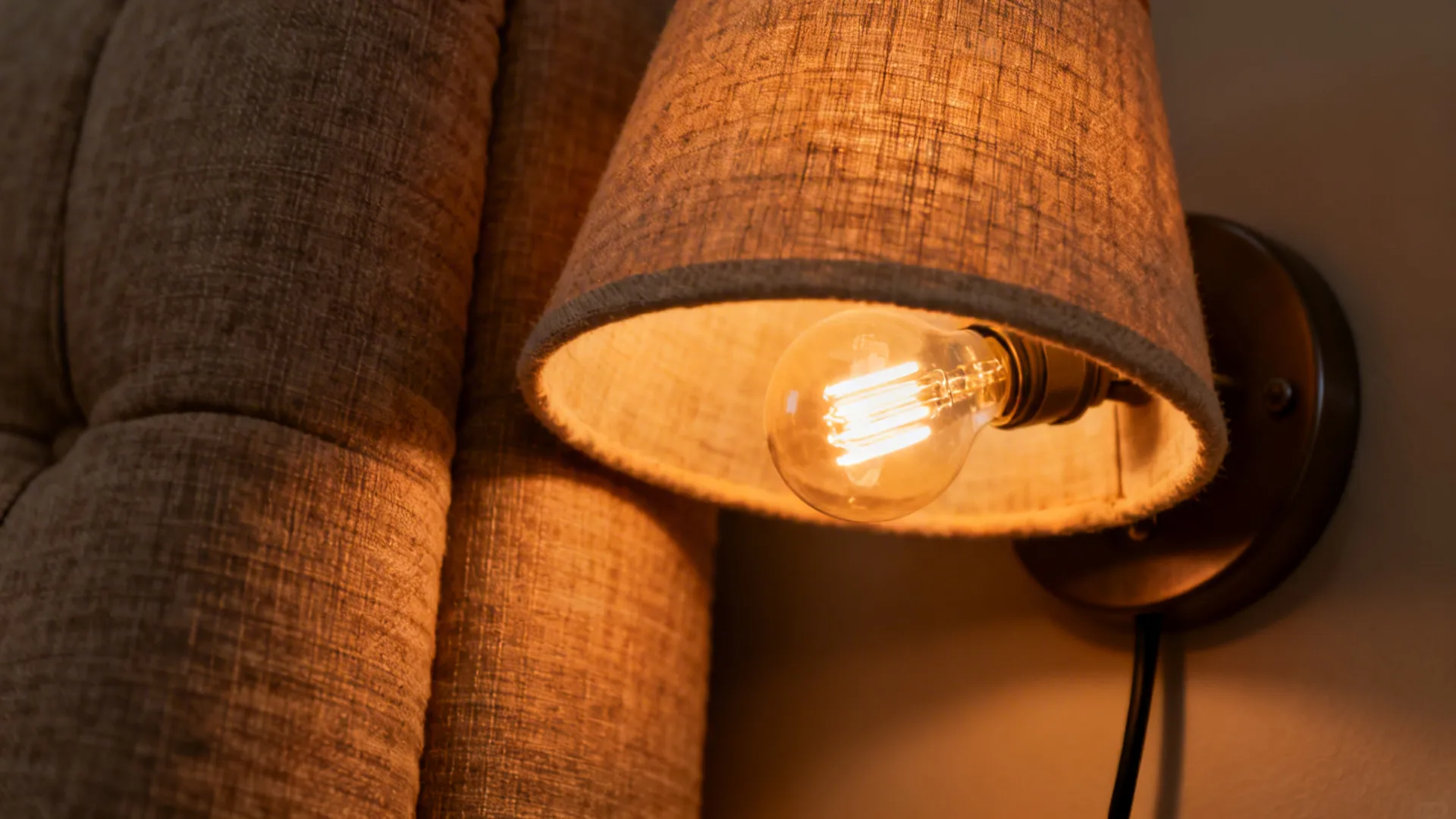 Close-up of a warm 2700K wall sconce beside washable linen fabric.