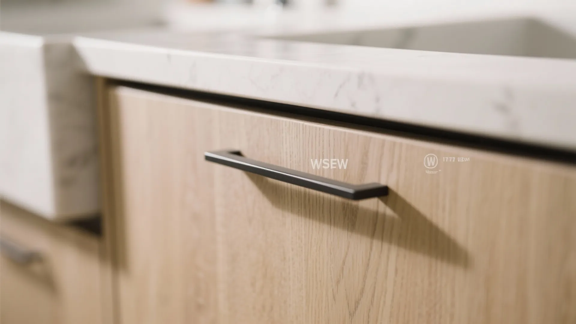 Close up of light wood kitchen cabinet with black handle and white marble stone countertop