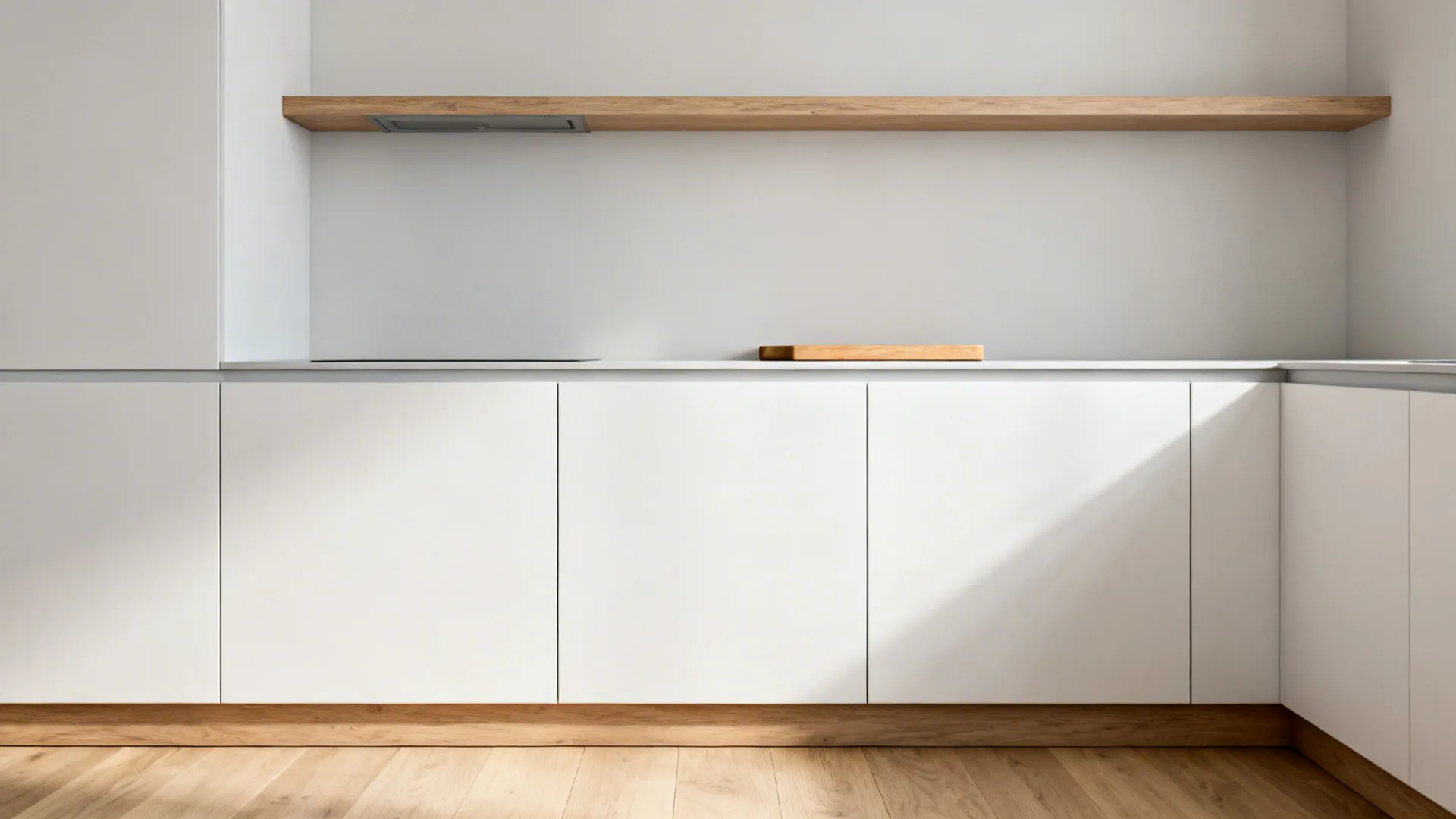 Matte white cabinets with a slim white-oak shelf and matching toe-kick in a small kitchen.
