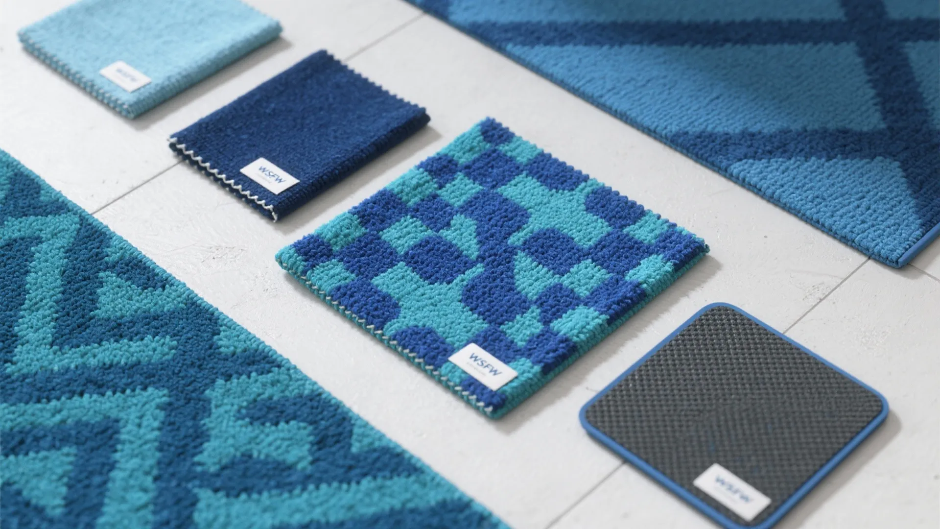 Flatlay of multiple washable blue rug samples and a thin non-slip pad for comparison.