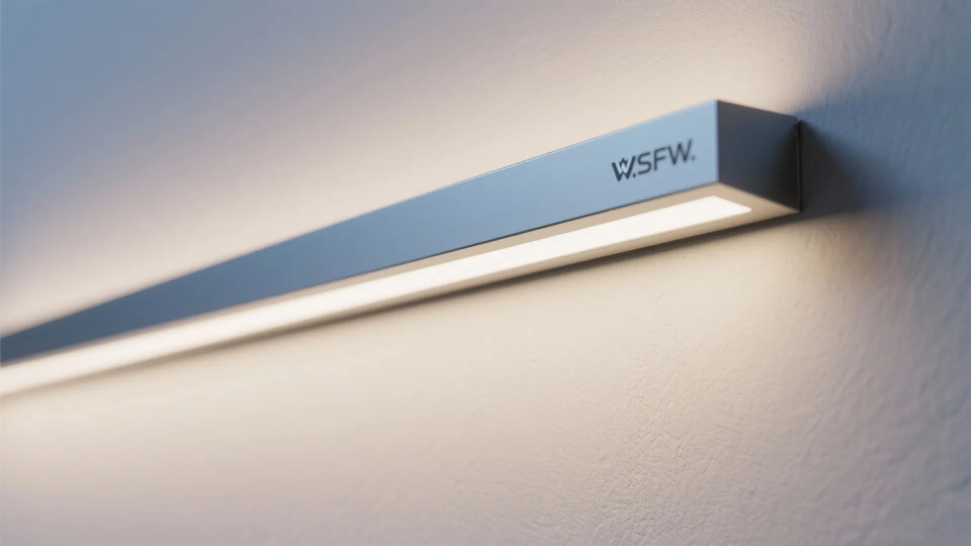 Close up shot of a slim silver light fixture mounted on a white textured wall