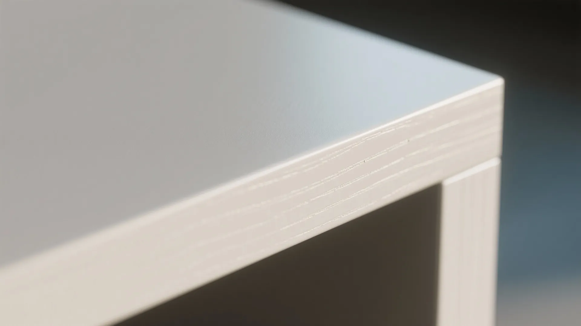 Close up of a white table corner showing smooth top surface and layered edge material details