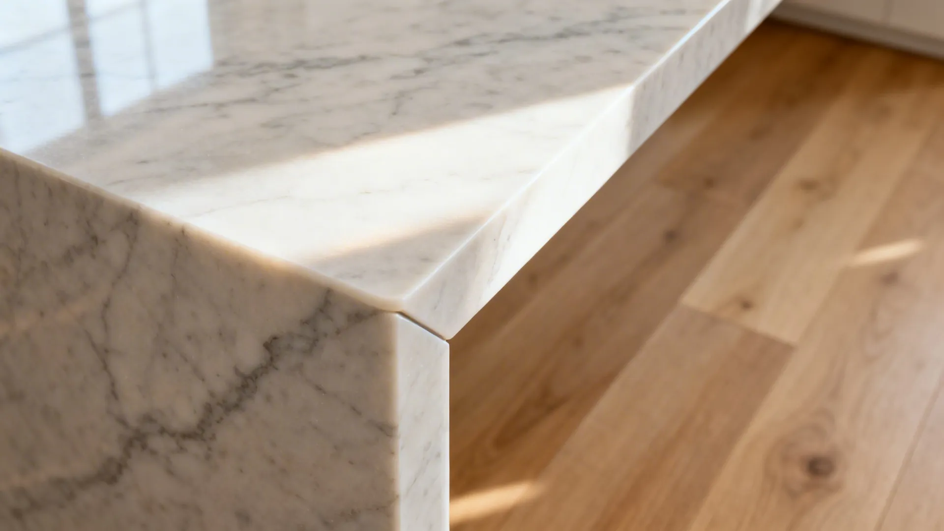 Close-up of a quartz waterfall island edge with tight miter over light oak floor.