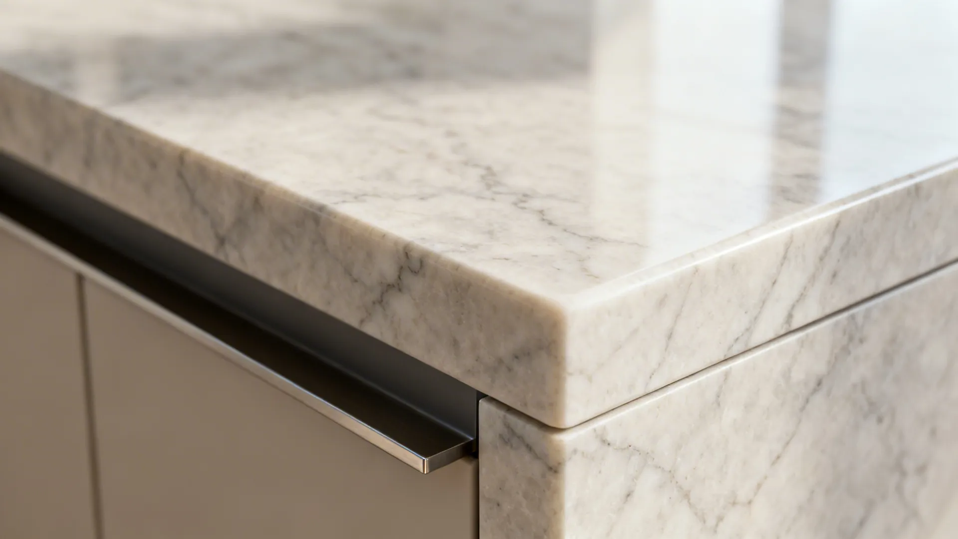 Close up of white marble countertop edge on a kitchen island with grey cabinet drawer underneath