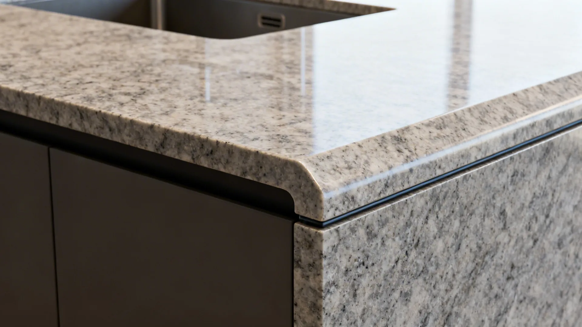 Close-up of waterfall granite edge with integrated undermount sink and ogee detail