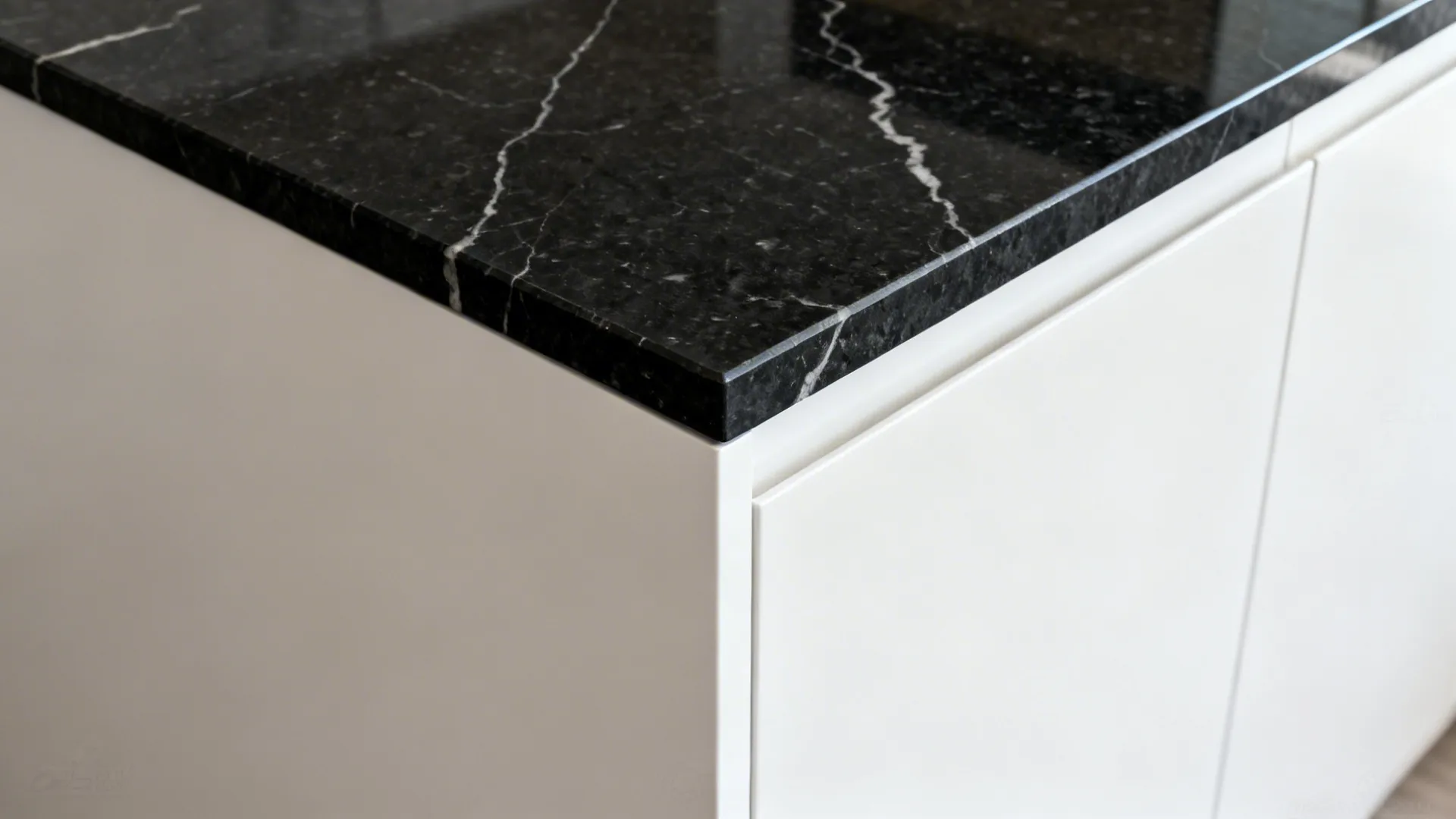 Mitered black granite waterfall joint aligned with veining next to white panel.
