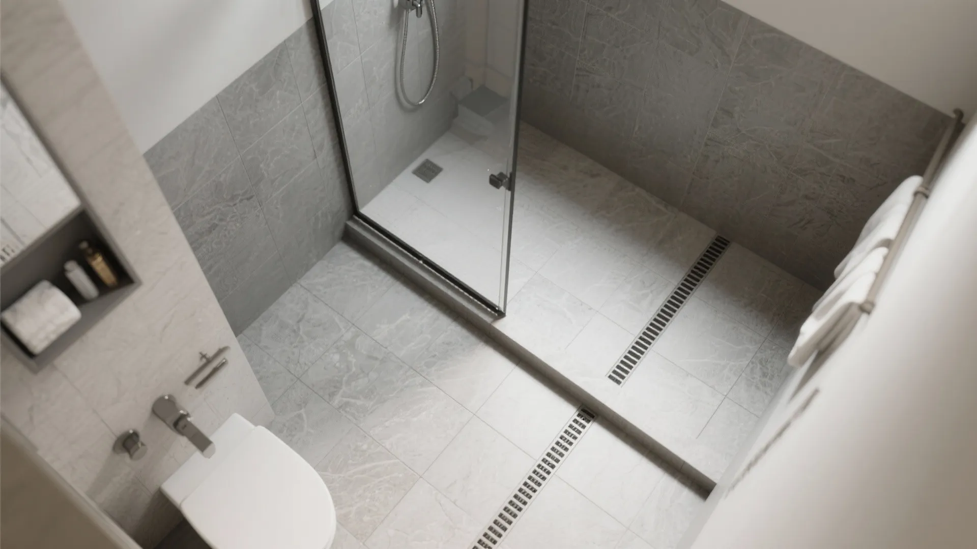 Modern wet room with grey stone tiles glass shower door white toilet and long floor drain