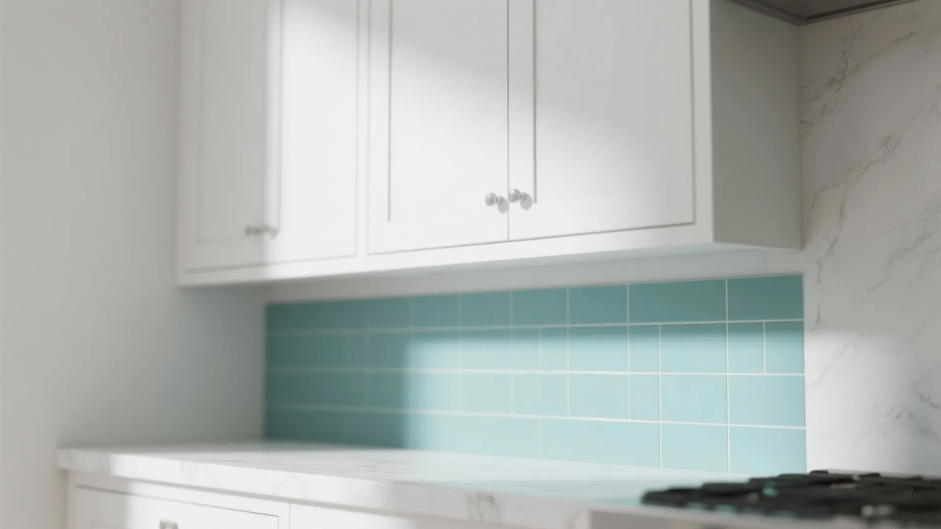 Close up of white kitchen cabinets above a light blue tiled wall with marble countertop surface