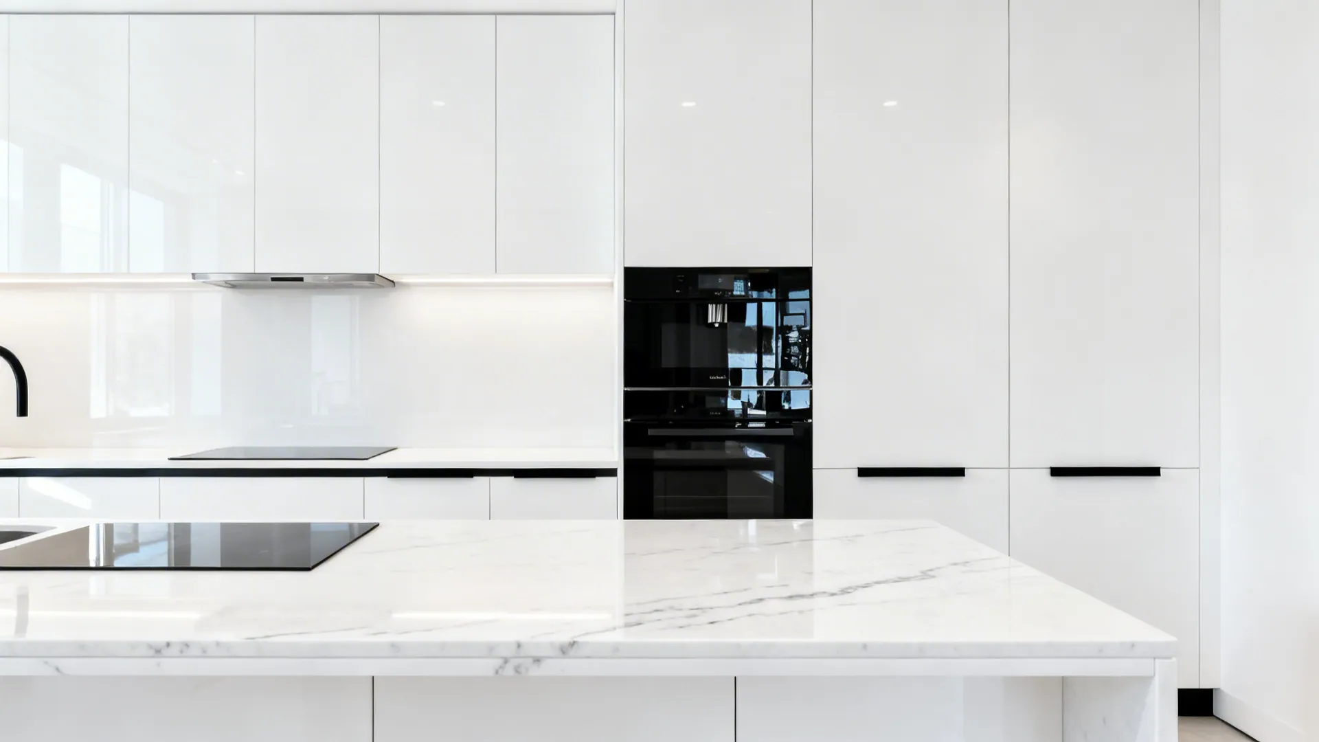 Crisp white cabinets with glossy black appliances and slim black hardware in a compact kitchen.