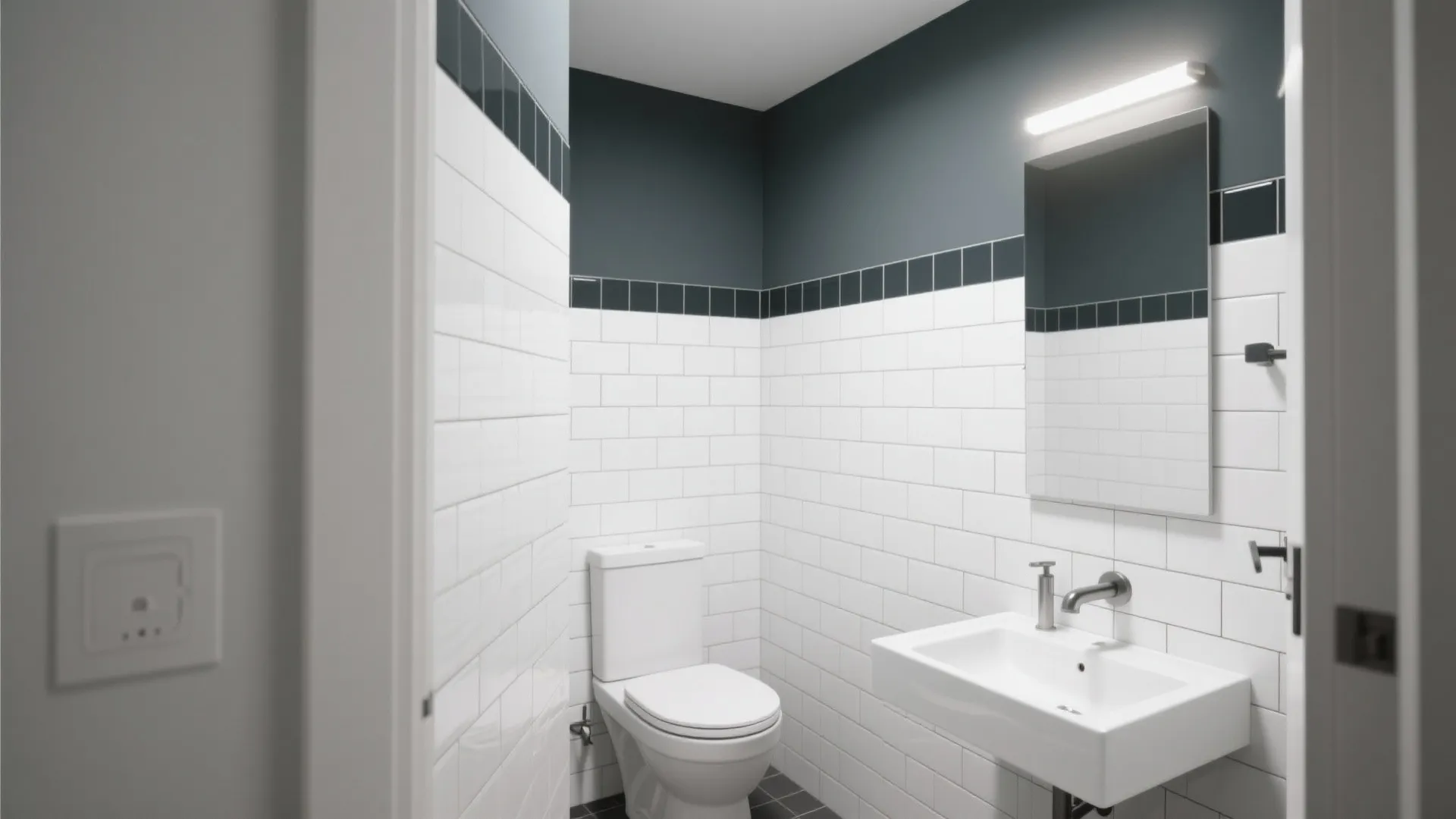 Small bathroom with white wall tiles dark blue upper walls toilet white sink and wall mirror