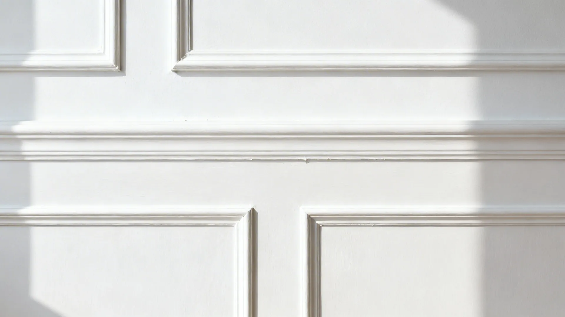 Subtle white molding and shallow paneling detail on a white wall