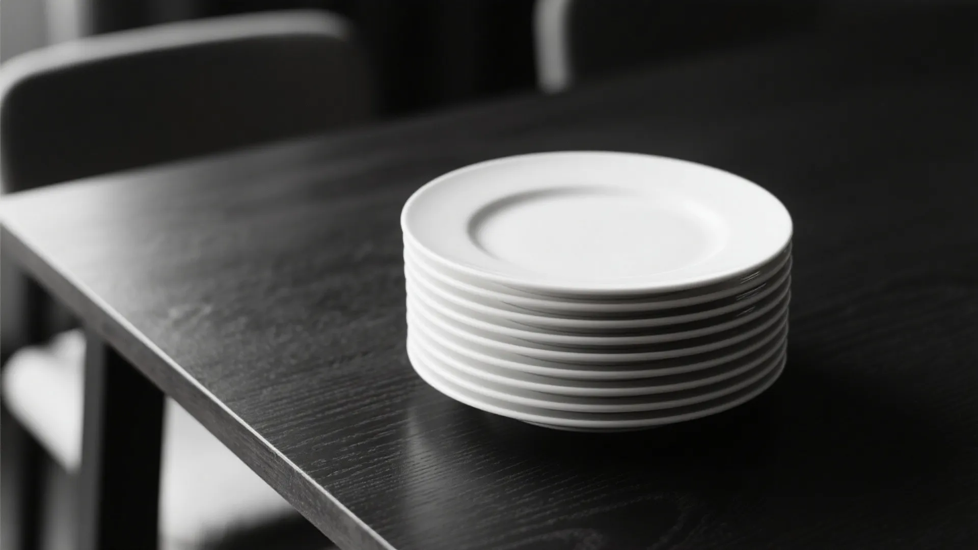 Stack of clean white ceramic dinner plates placed on a dark black wooden dining table