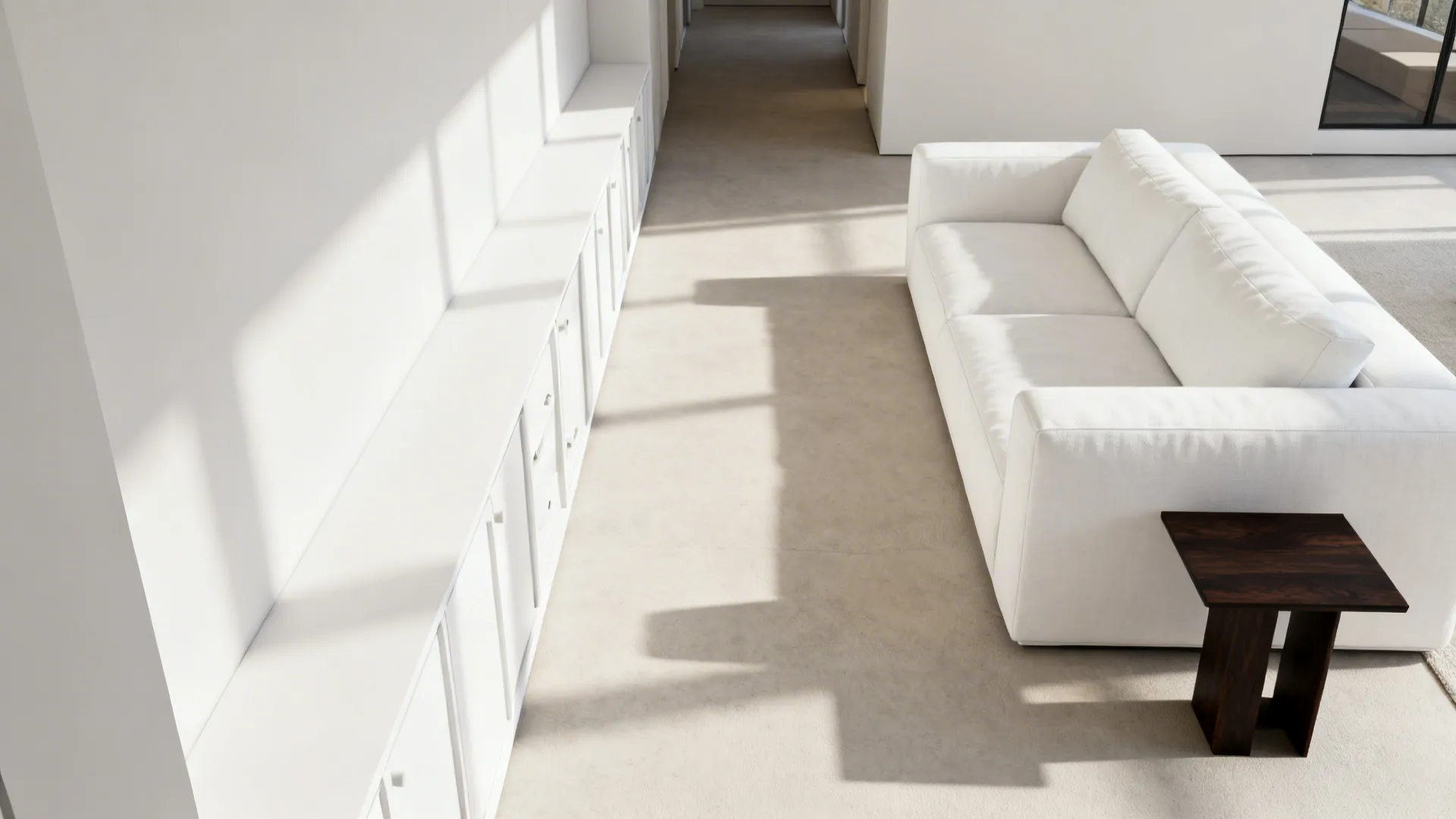 Bright minimalist living space with long white cabinet, white sofa, dark side table, and natural light