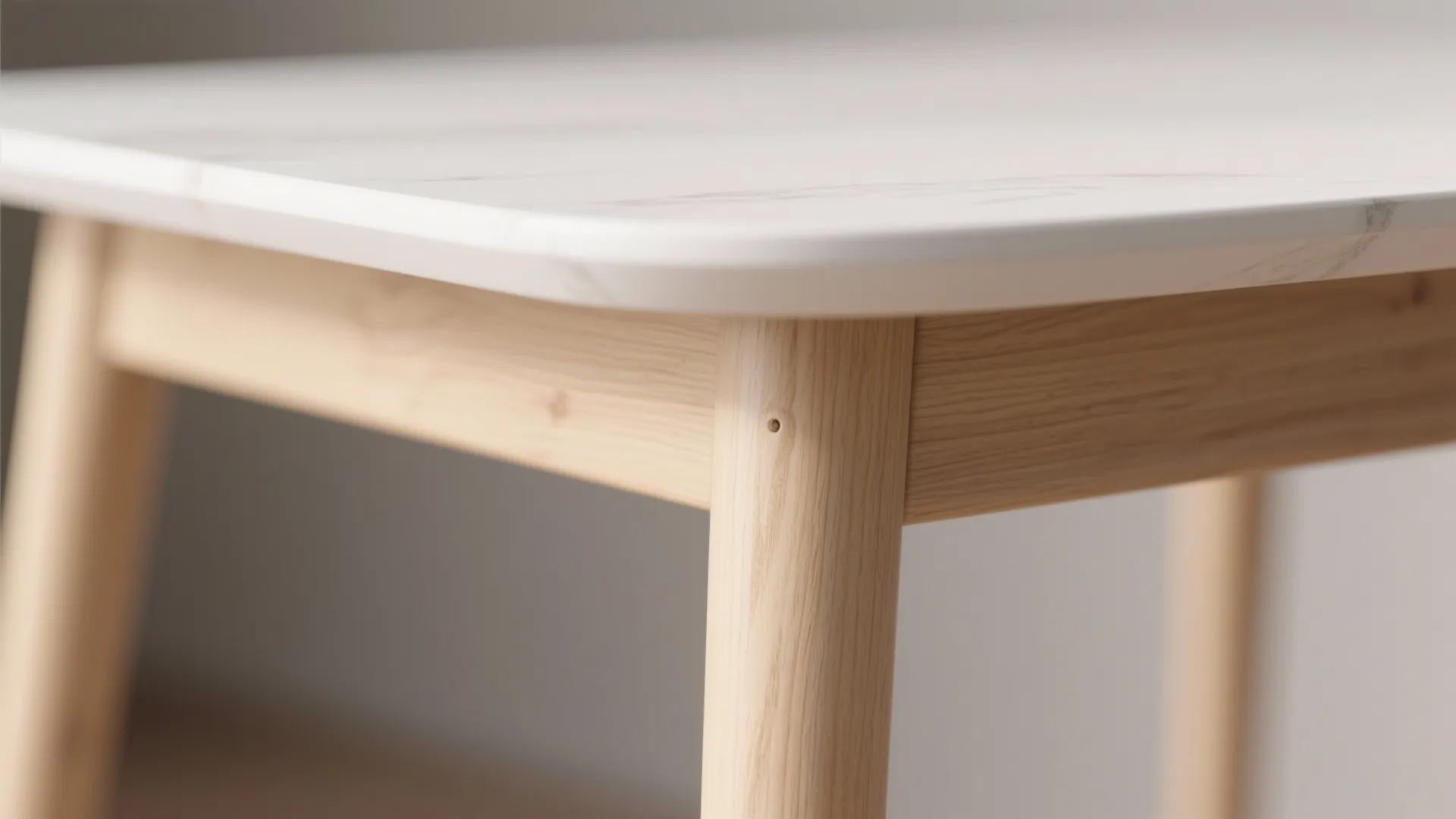 Close up view of a modern dining table with white marble top and wooden legs