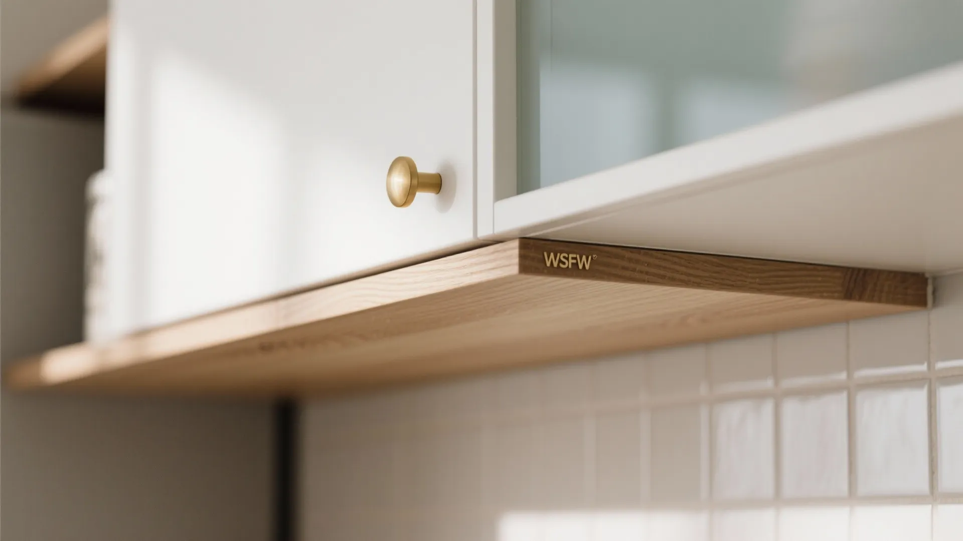 Close-up of teak-look laminate shelf with brass hardware in a white modern kitchen.