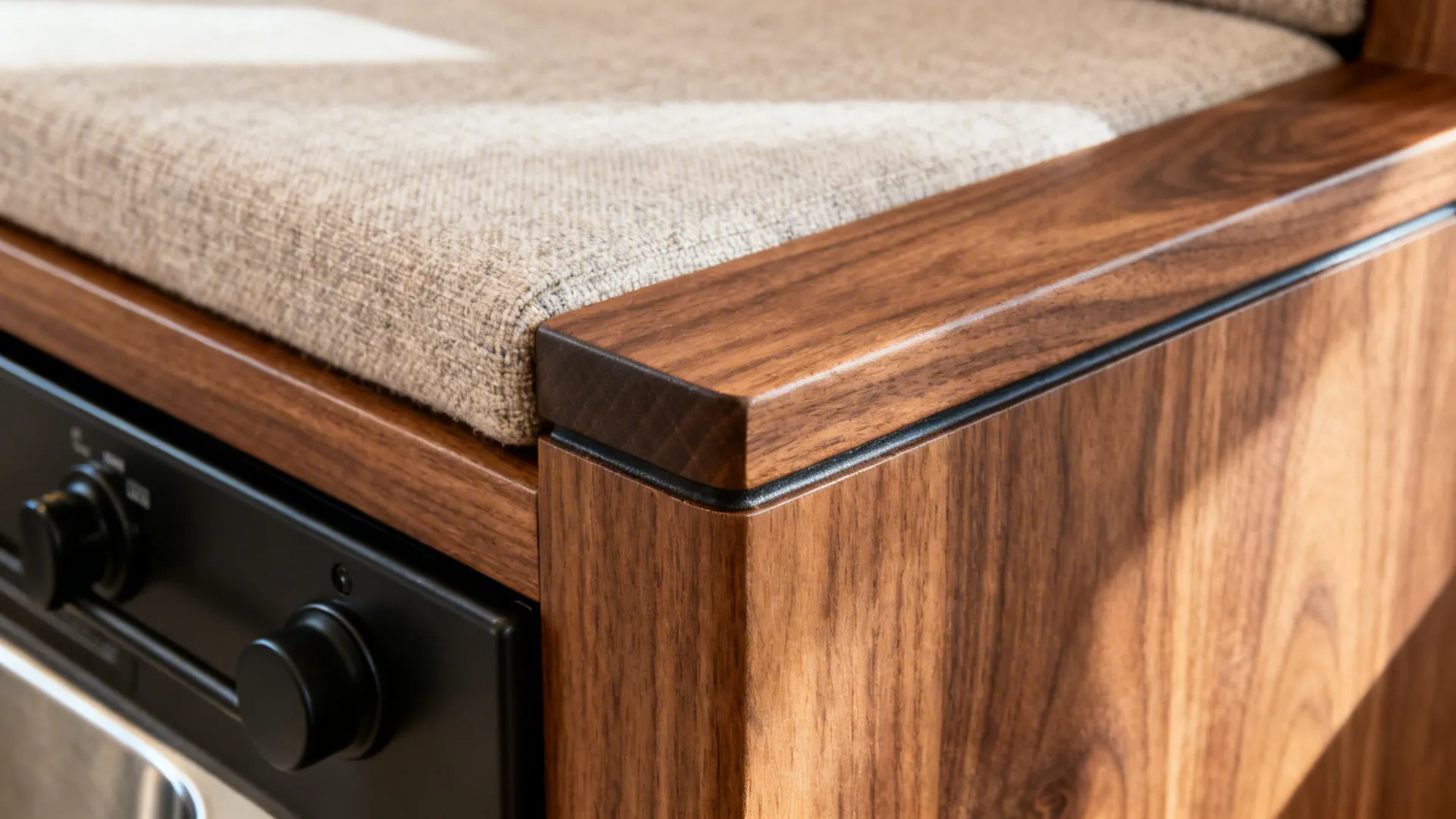 Close up view of wood cabinet with fabric seat cushion and black oven control knobs