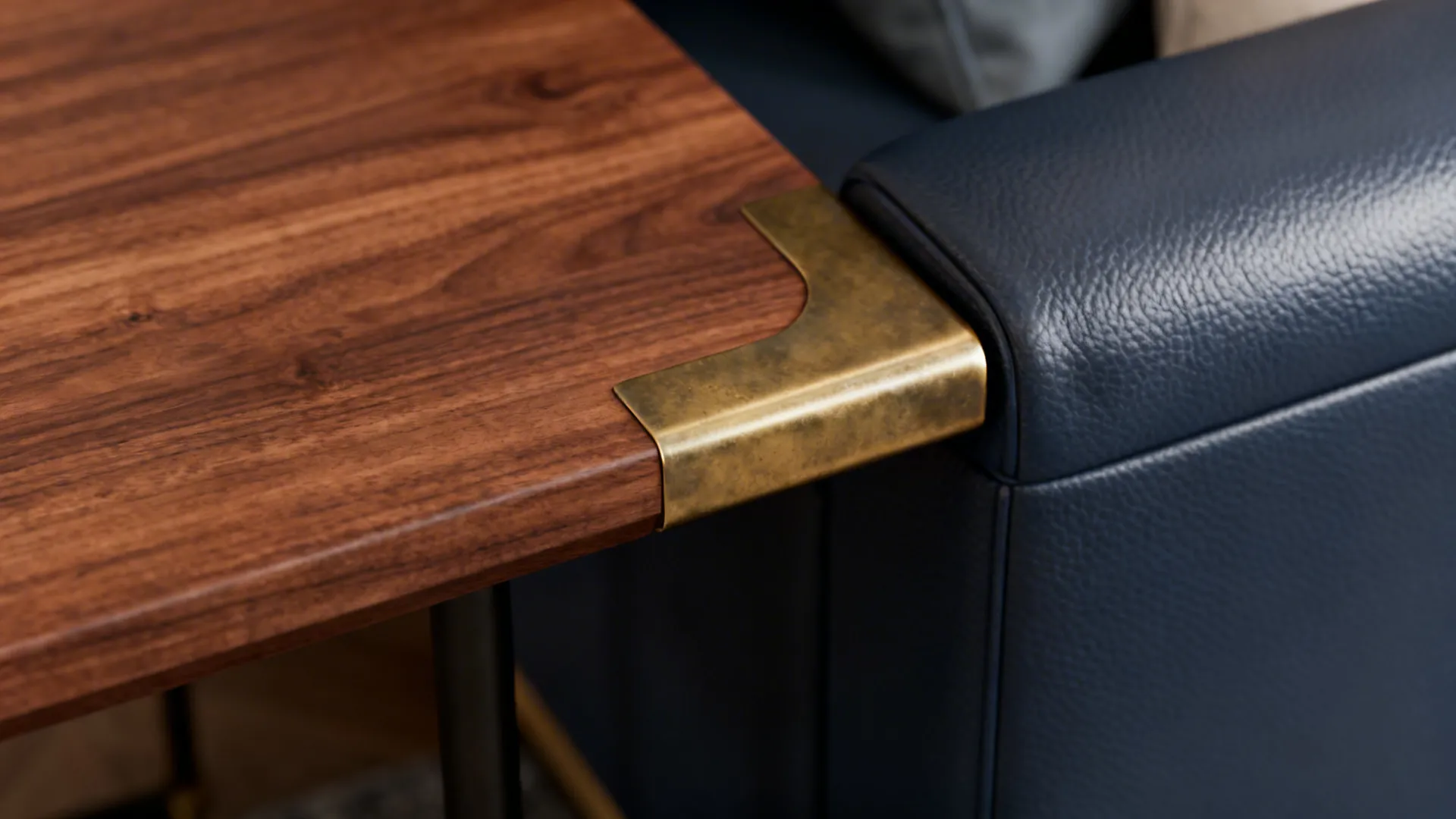 Close-up of walnut table and brushed brass coffee table beside a navy leather sofa.
