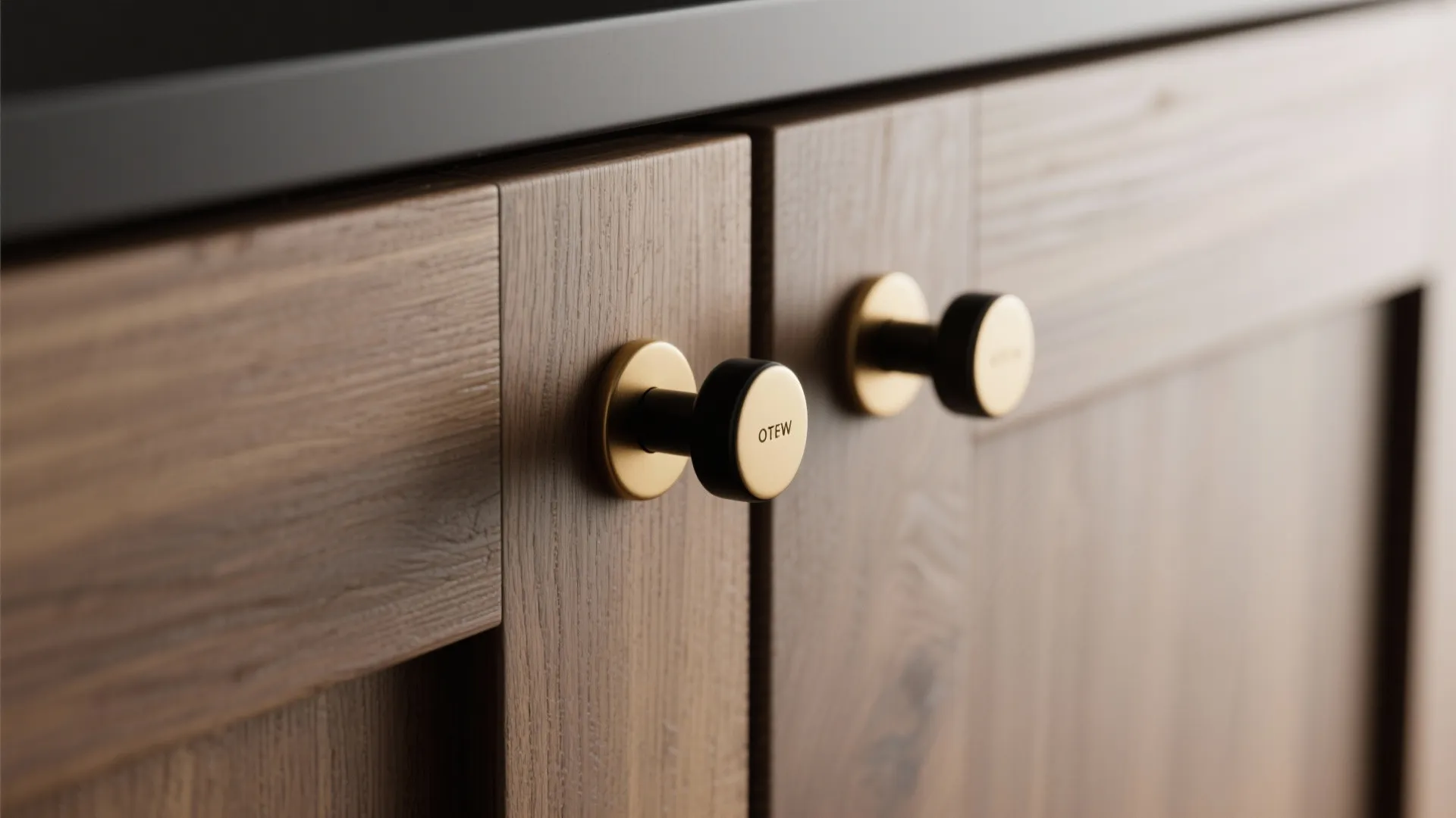 Close up view of round gold and black handles on dark wood kitchen cabinet door panels
