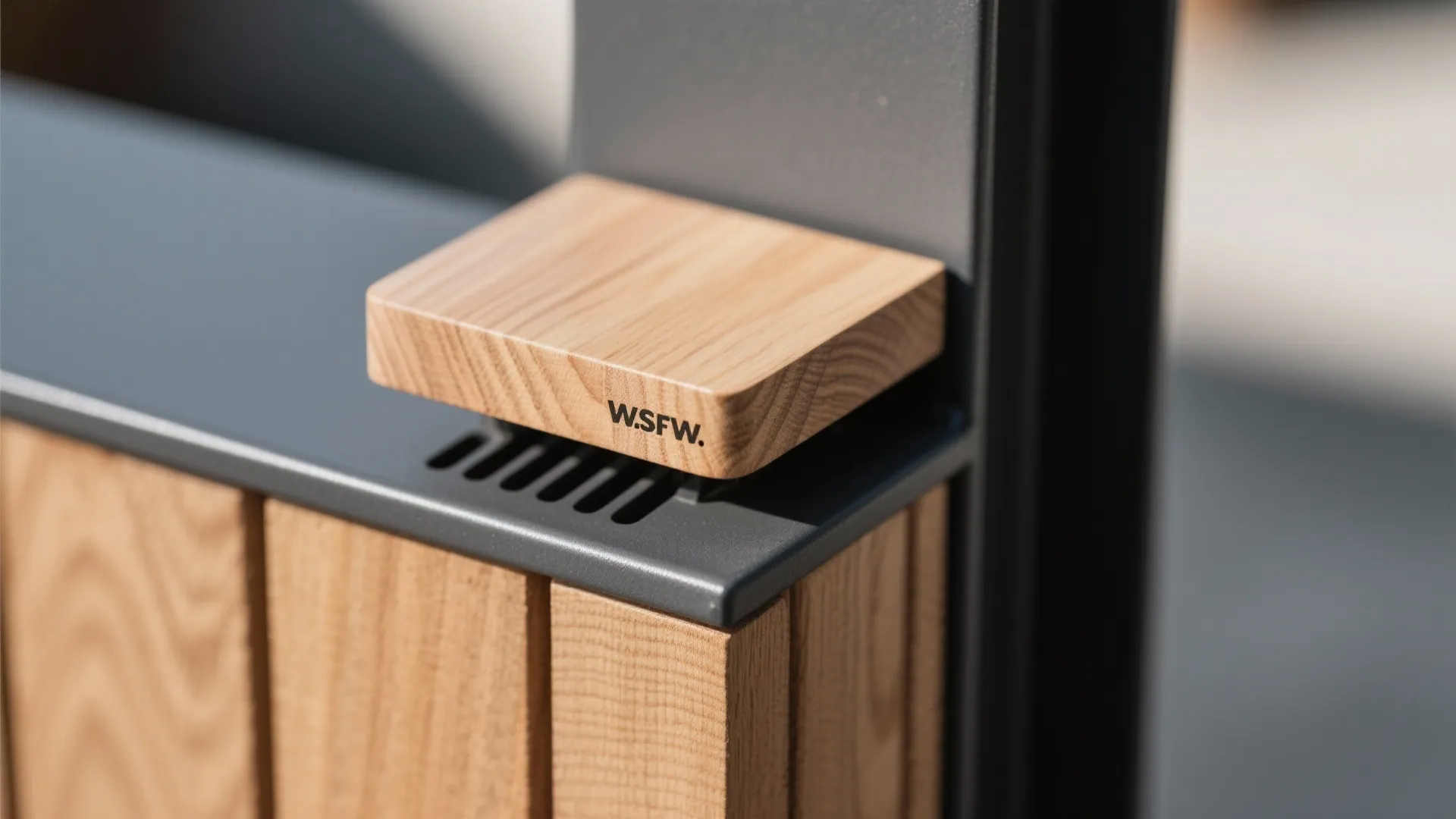 Macro of wood cap and matte dark steel post junction with fine grain and clean finish.