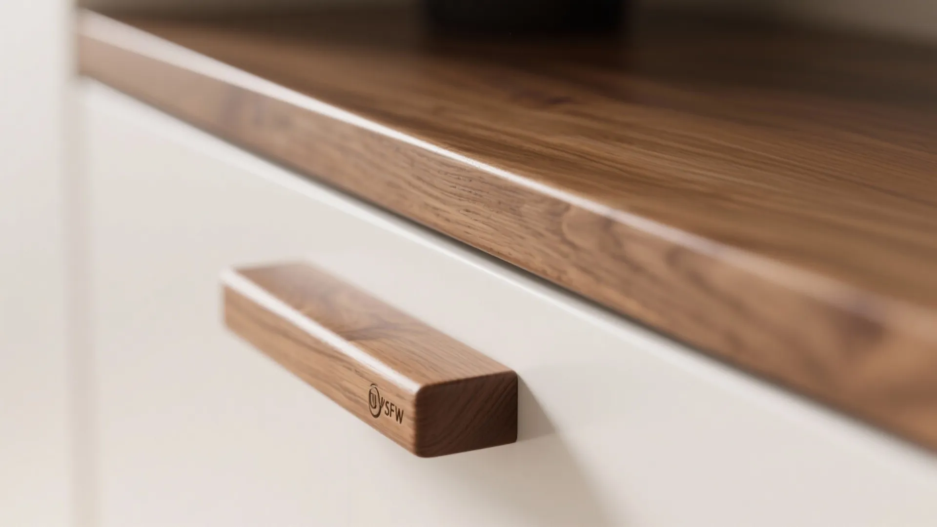 Close up of wooden handle on white cabinet door with matching wood surface in kitchen