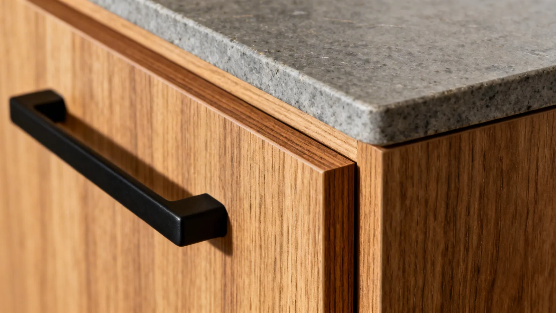 Close-up of wood-look laminate door with solid edge banding and matte black hardware under warm light.