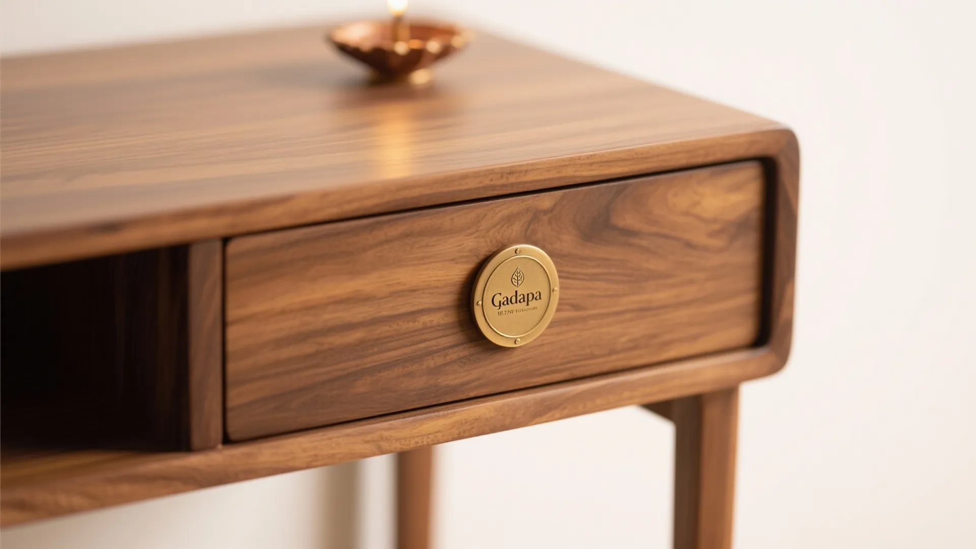 Macro of teak veneer gadapa with a concealed drawer and brass diya plate.