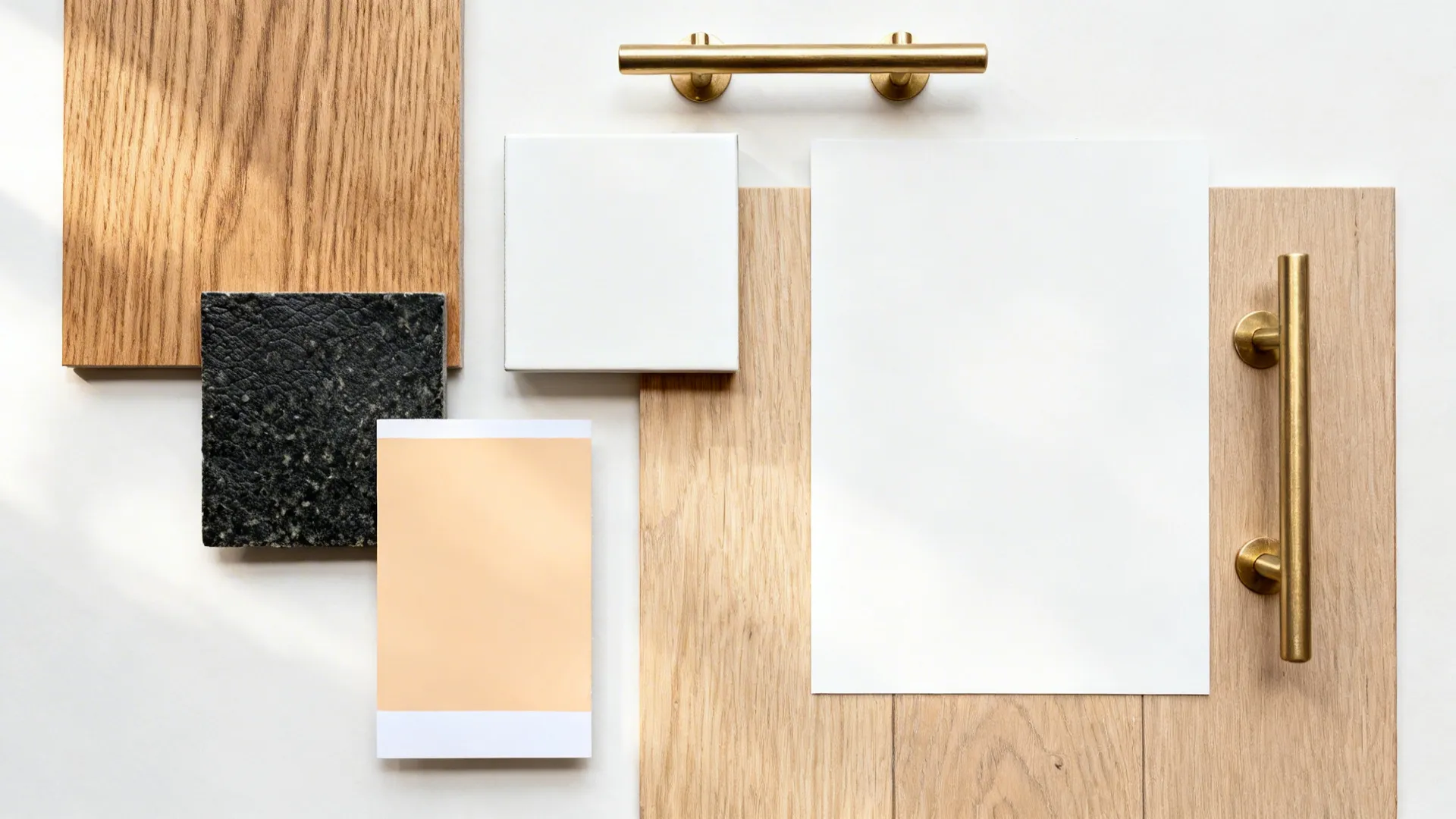 Flatlay of oak, black granite, white lacquer, brass hardware, and flooring samples.
