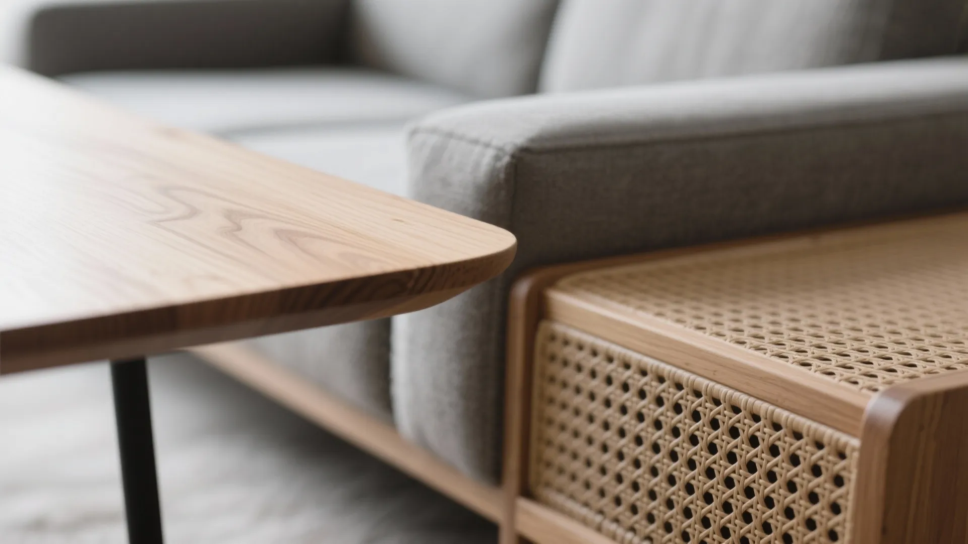 Close up view of wooden coffee table next to grey sofa and rattan storage cabinet