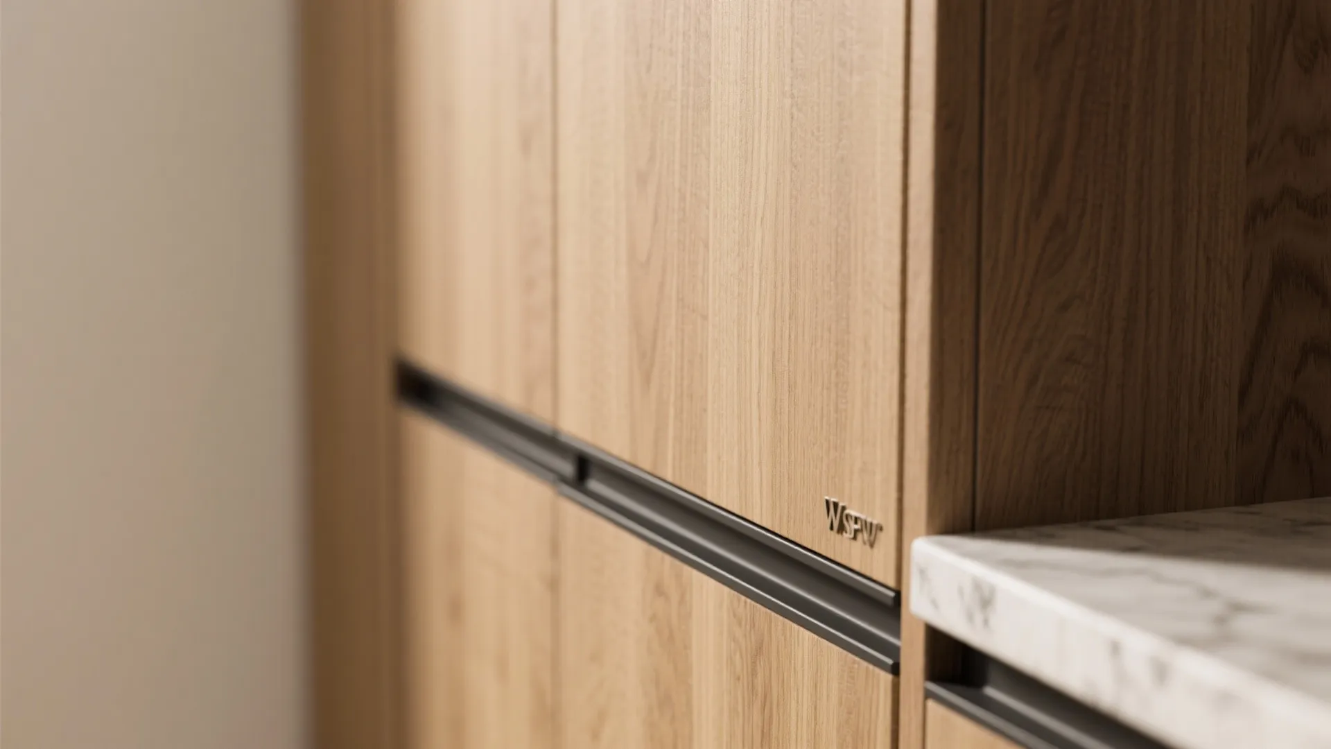 Close up view of natural wood grain cabinet doors with black handles and white countertop