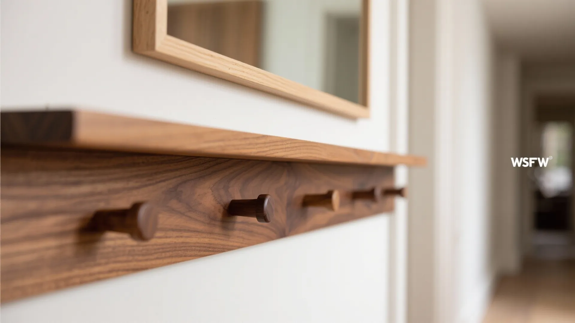 Close up view of a wooden wall shelf with hooks and a framed wall mirror