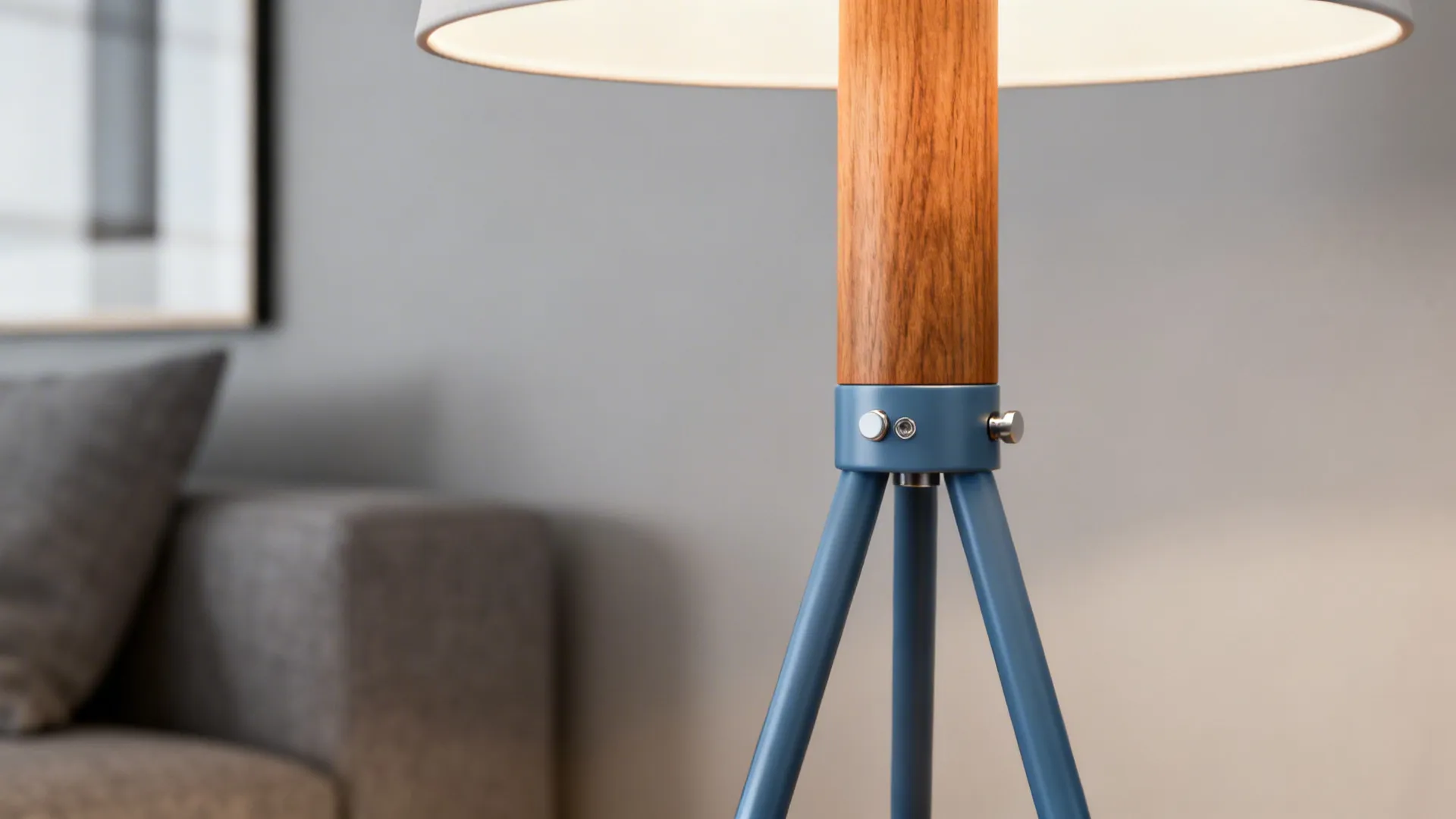 Close up of floor lamp with wooden neck blue metal tripod legs and grey sofa