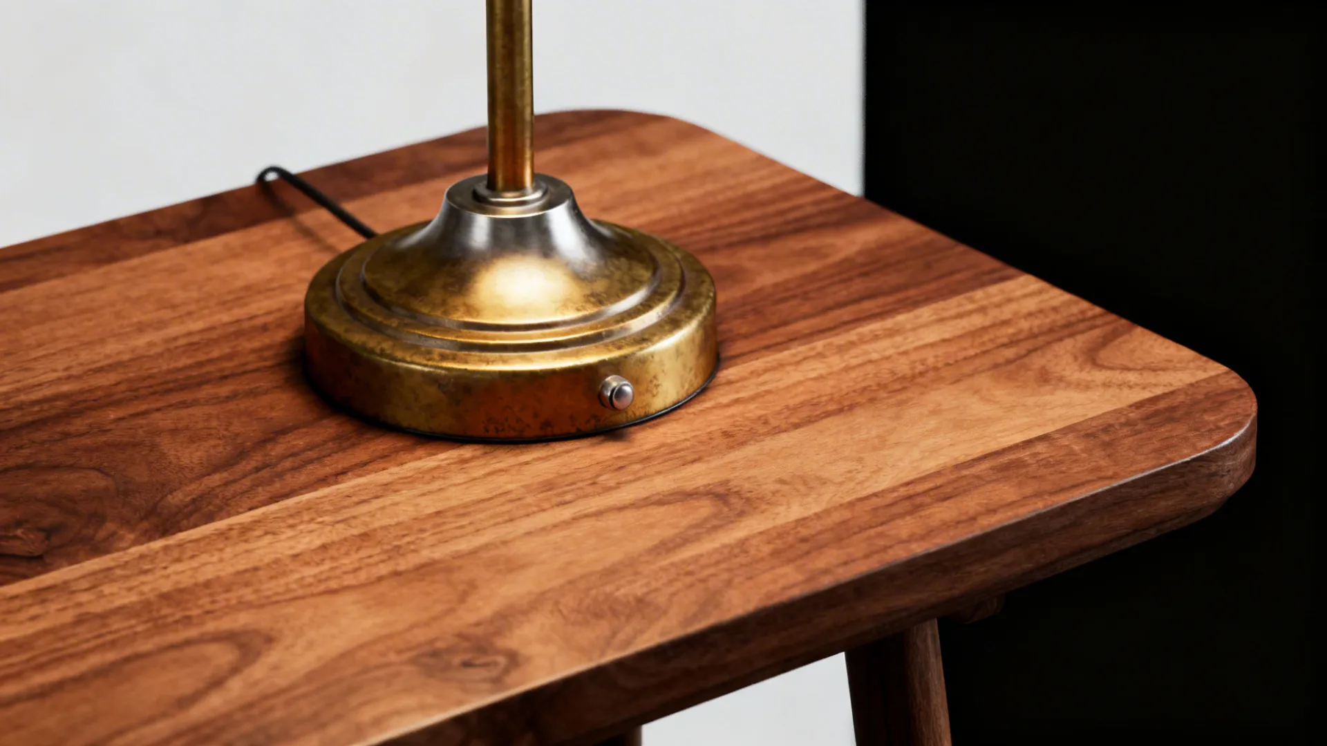 Walnut side table with brass lamp base and brushed nickel fixture in a monochrome living room.