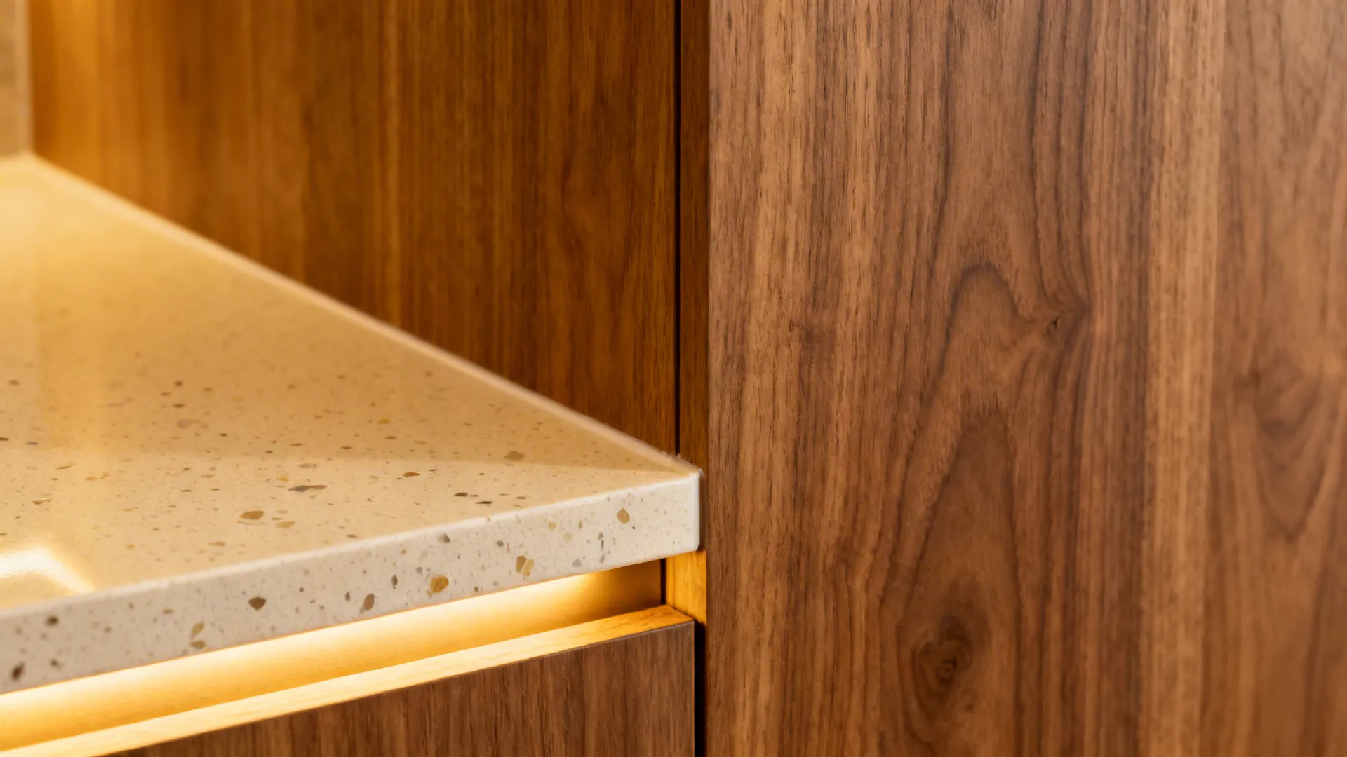 Macro of oak laminate cabinet meeting a light quartz countertop with soft LED glow.